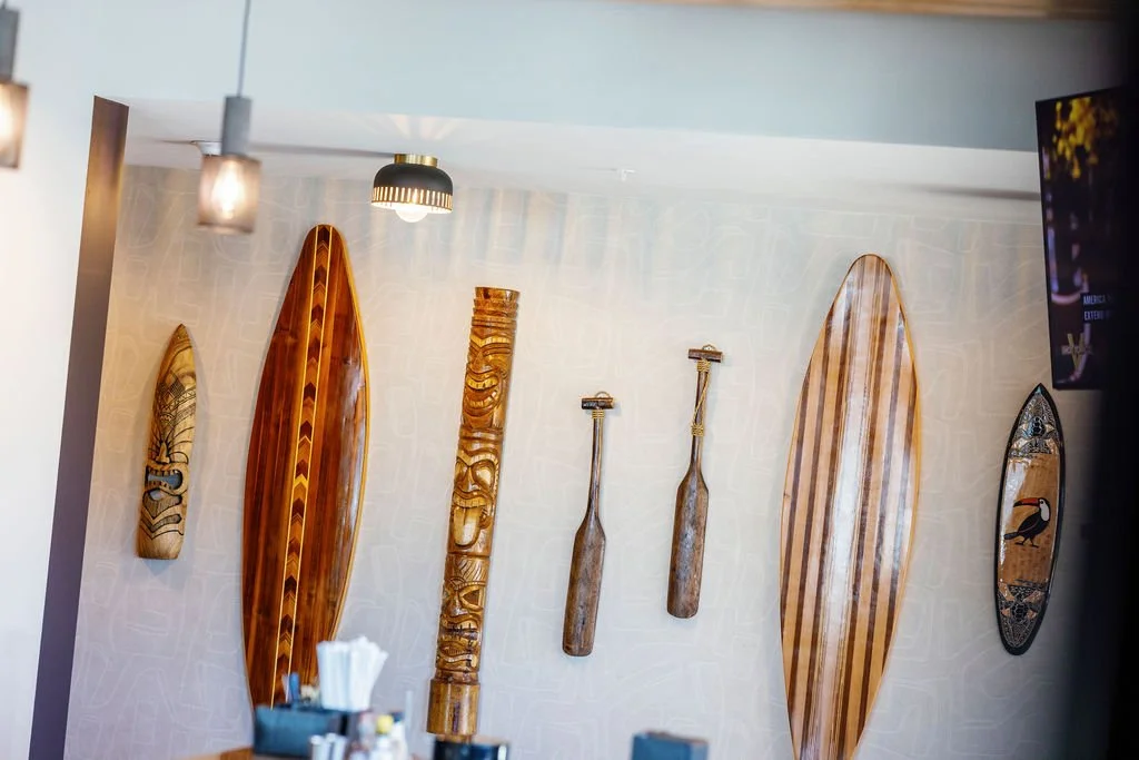 Wall with various decorative wooden paddle and surfboard art pieces.