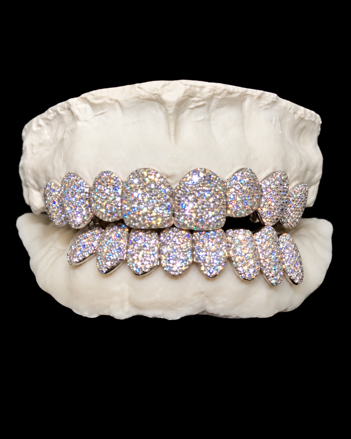 A set of diamond-encrusted grillz on a dental mold, displayed against a black background.