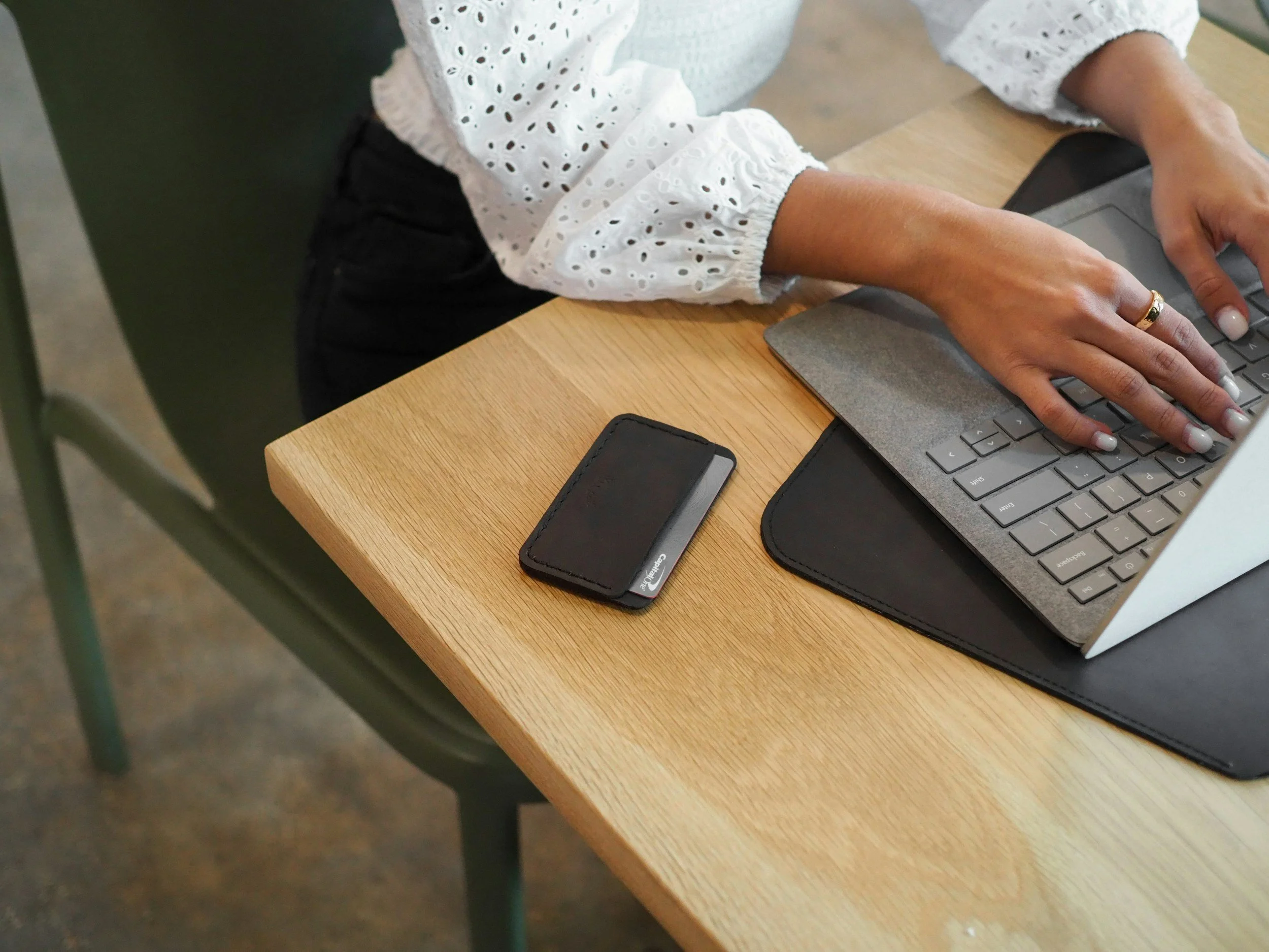 A woman is typing on laptop, and her cell phone is next to herphone are on a desk