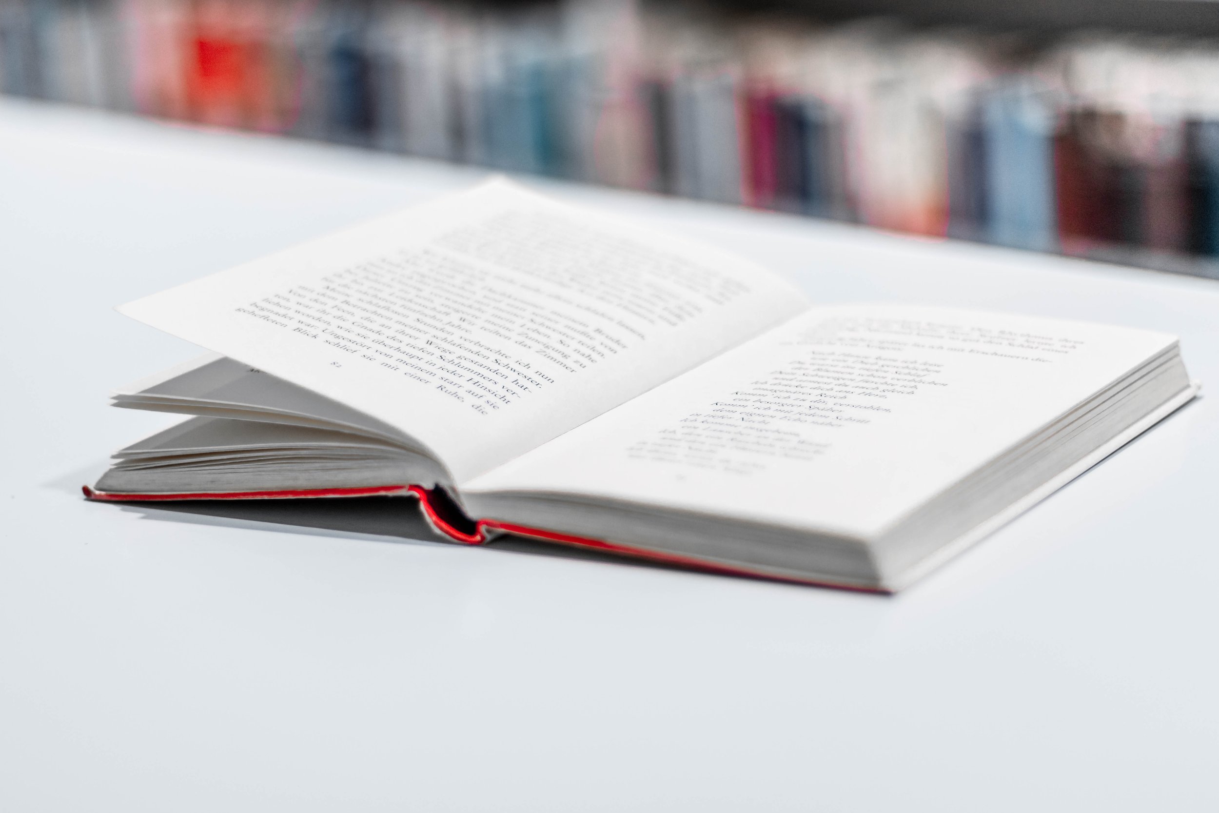 An open books lies on a table in a library. Shows book editing and proofreading services