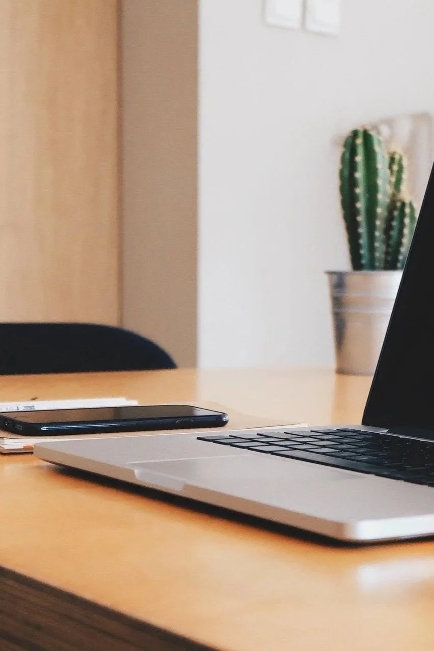 A desk with a cell phone and laptop on it