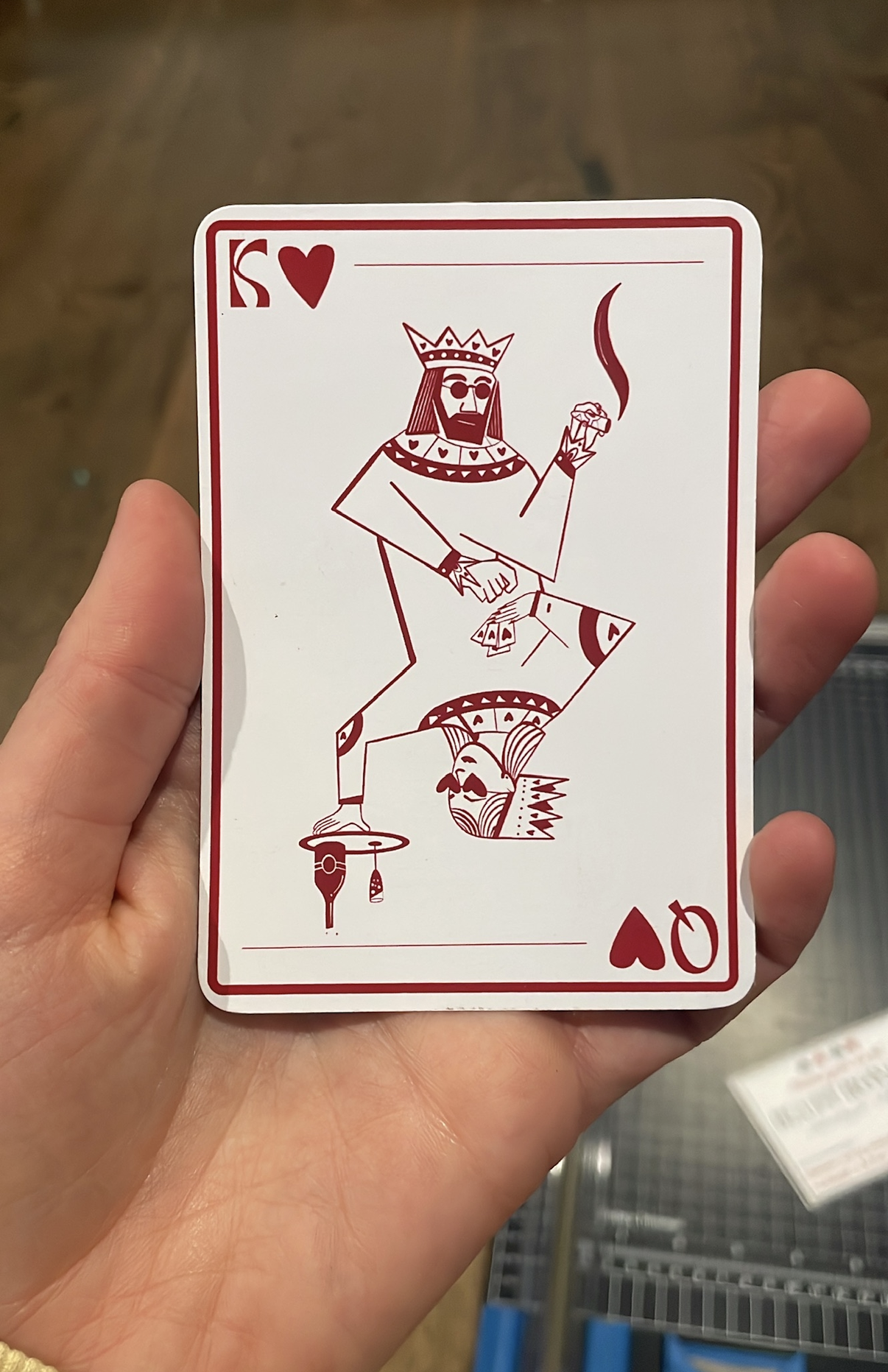 A playing card featuring an illustration of a king with sunglasses, a beard, a crown, and a cigar, with a stylized face and body, and the number 10 and heart symbol in the corner.