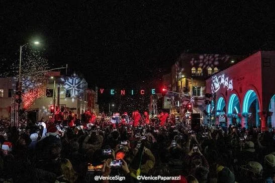 Crowd at the Venice holiday sign lighting on Windward Avenue, with the Venice sign lit in festive colors