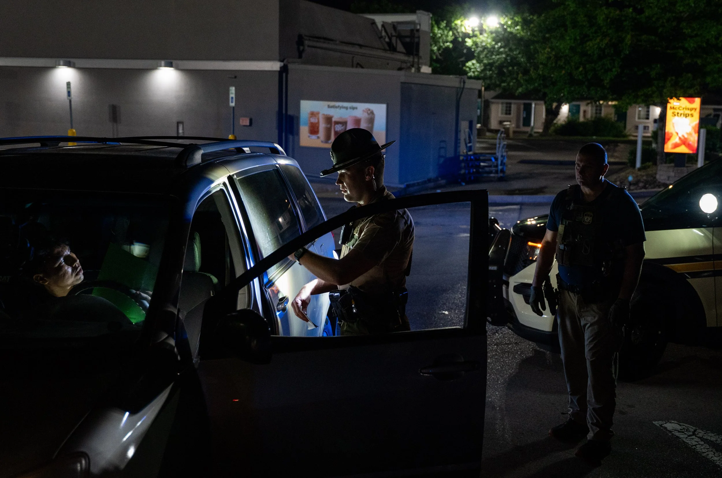  A Tennessee Highway Patrol (THP) officer conducts a traffic stop while a U.S. Immigration and Customs Enforcement (ICE) officer looks on during an operation conducted by ICE along with THP to detain noncitizens across the city of Nashville, in South