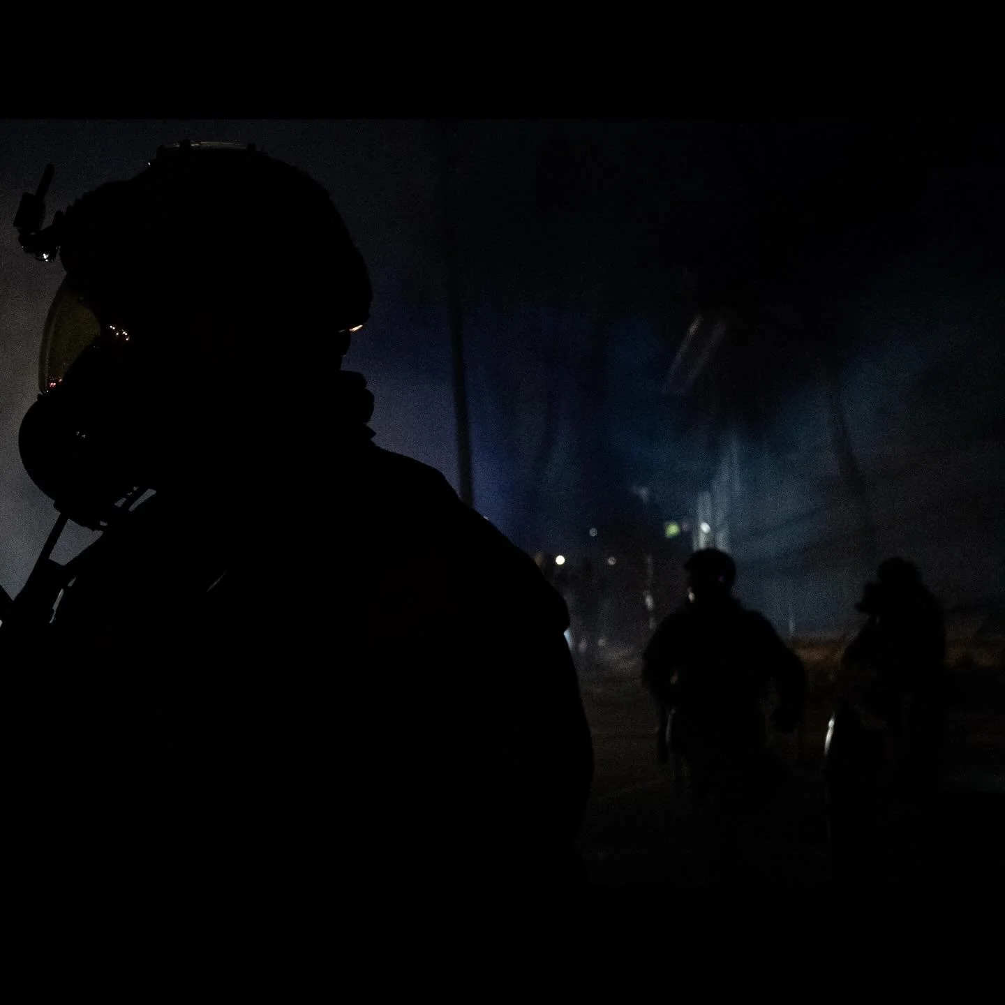 A U.S. federal agent looks on after using tear gas on angered community members, as tensions rise after federal agents were involved in a shooting incident, a week after a U.S. Immigration and Customs Enforcement (ICE) agent fatally shot Renee Nicole