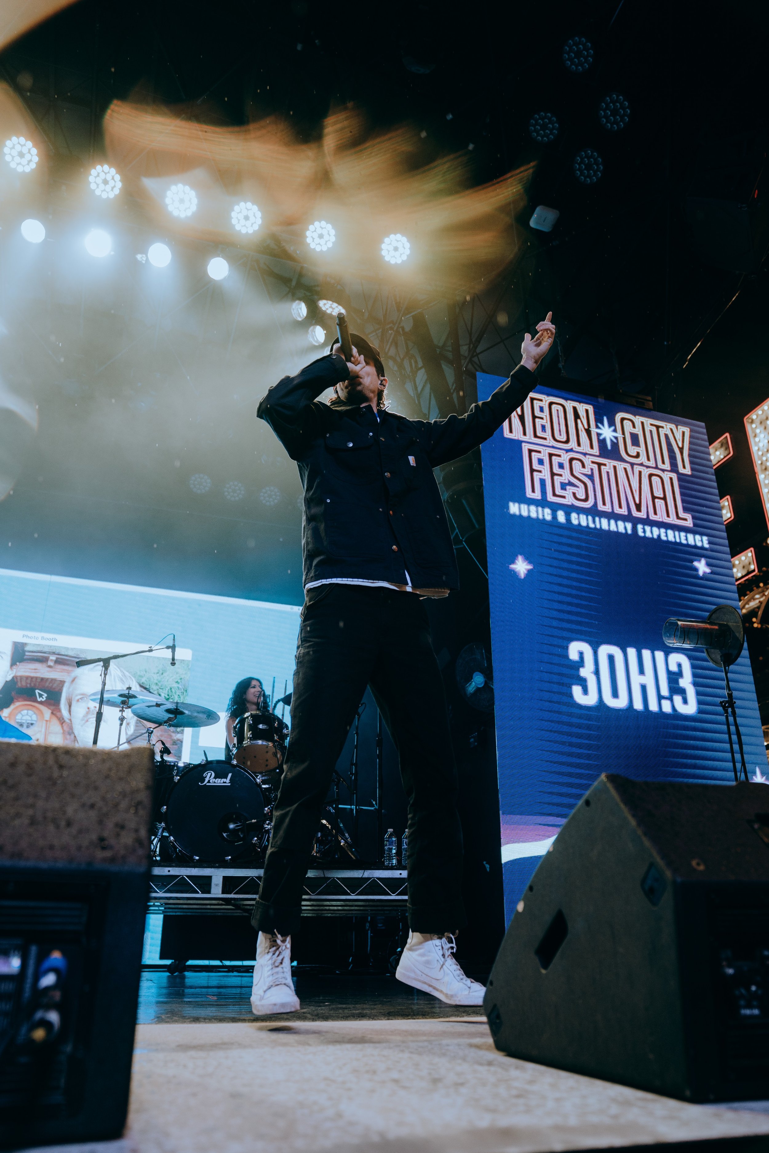 Musician performing on stage at Leoń City Festival with a large screen displaying event details in the background.