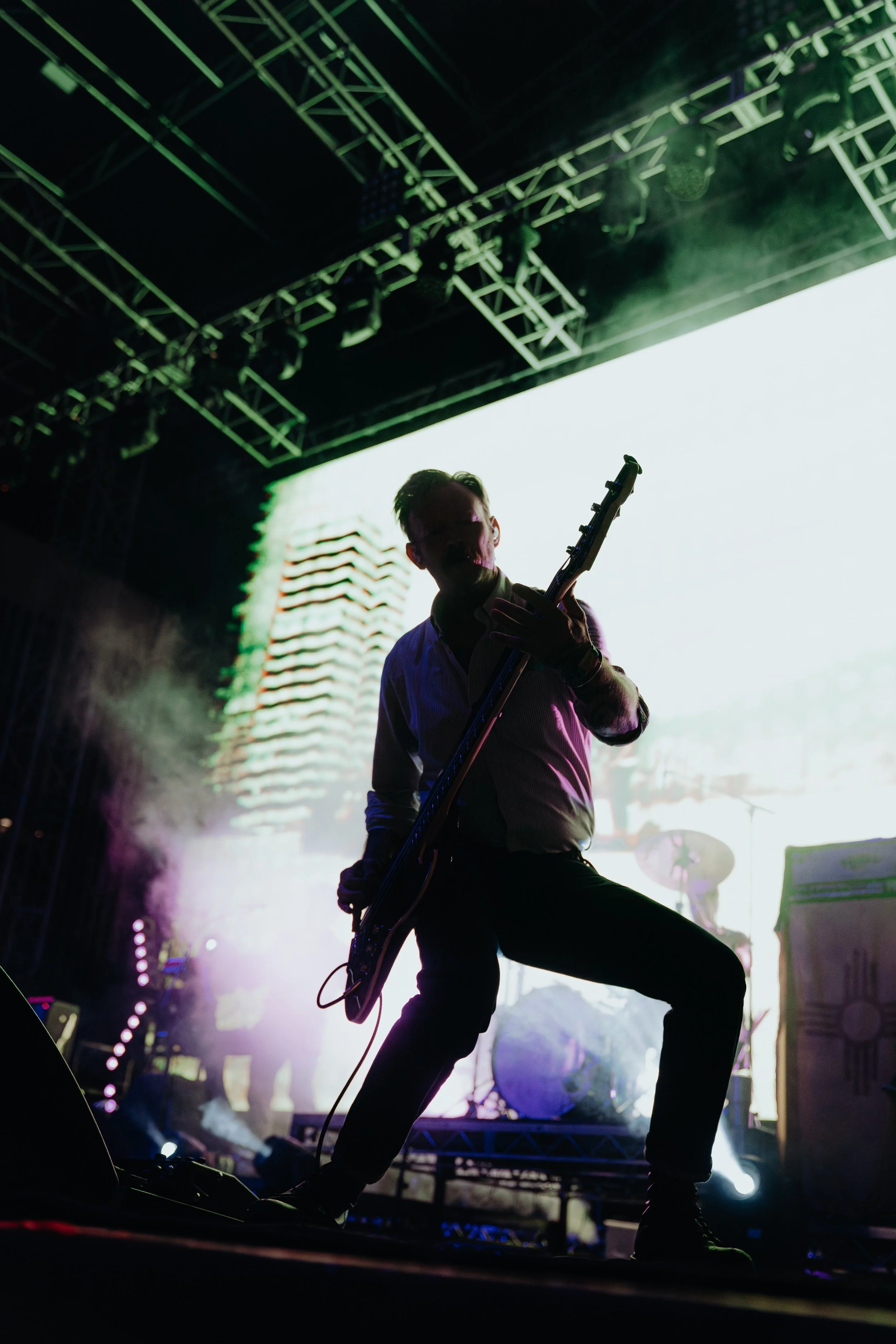 A musician playing an electric guitar on stage during a concert, with stage lights and fog creating a dramatic atmosphere.