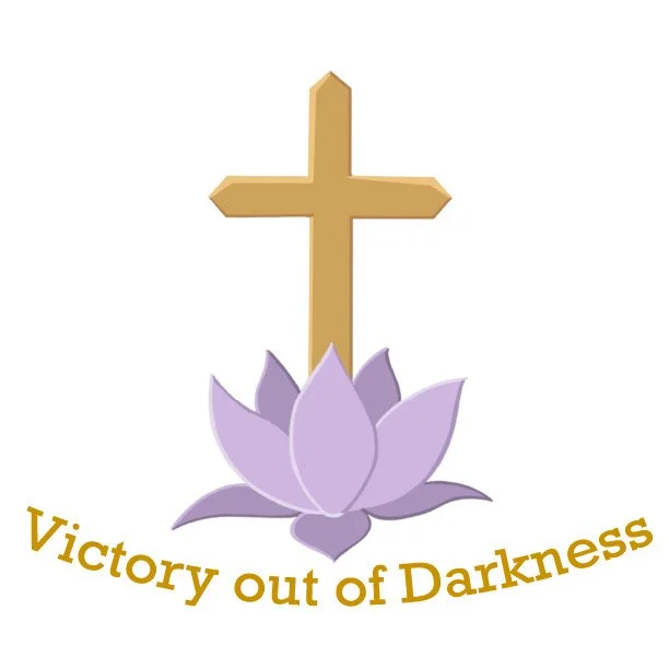 A gold cross above a purple lotus flower with the phrase "Victory out of Darkness" curved below.