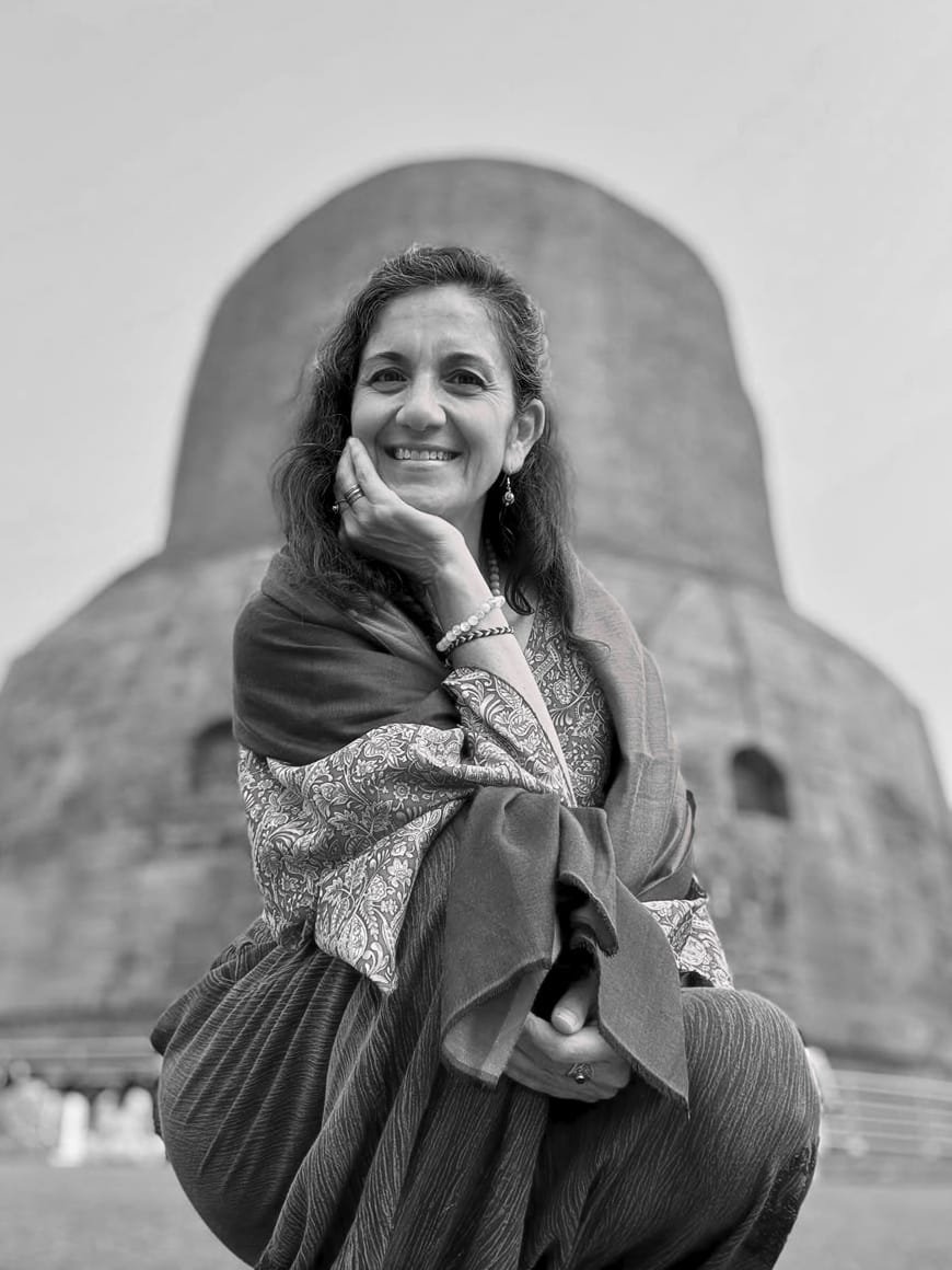 Clara Rivera sonriendo, sentada frente a una Stupa en Varanasi. En blanco y negro.