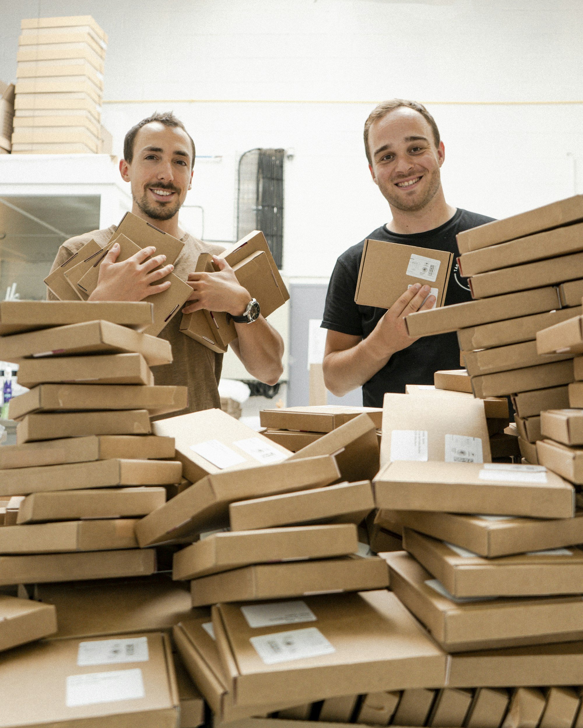Two people packing cardboard boxes in a workspace.