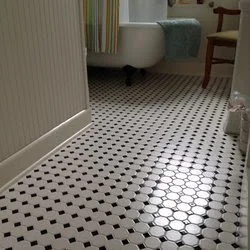Floor with black and white hexagonal tiles in a room with a radiator, a sofa, and an armchair.