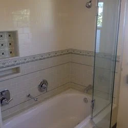 Bathroom with bathtub, shower fixtures, and tile walls