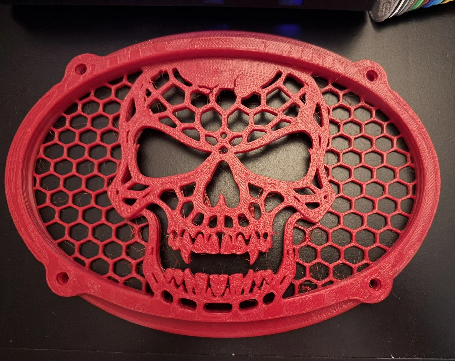 Red skull-shaped object with a honeycomb pattern and a spider web design on top.