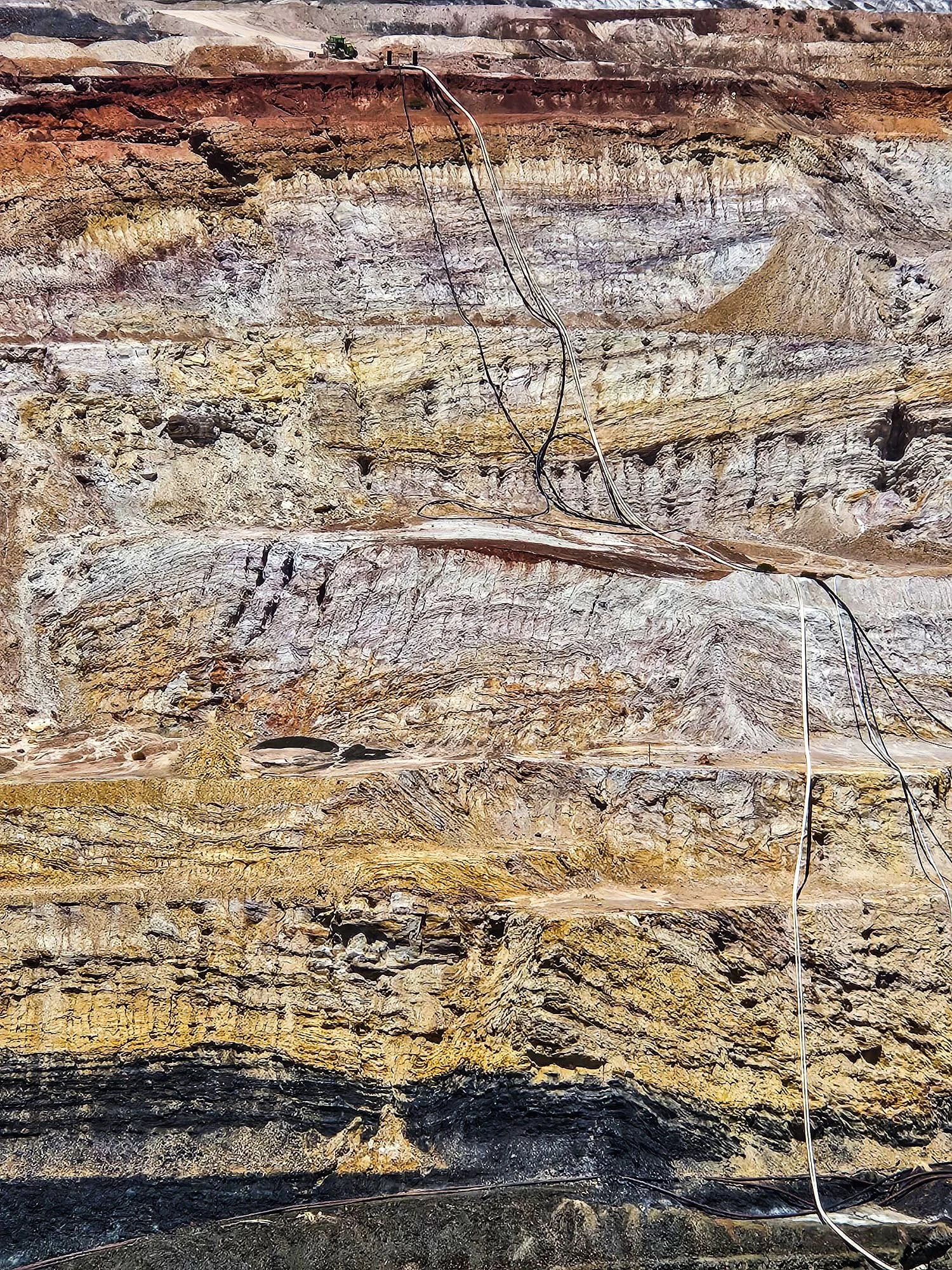 Close-up of valuable minerals and ice in underground mine tunnel, with electrical wires and equipment visible.