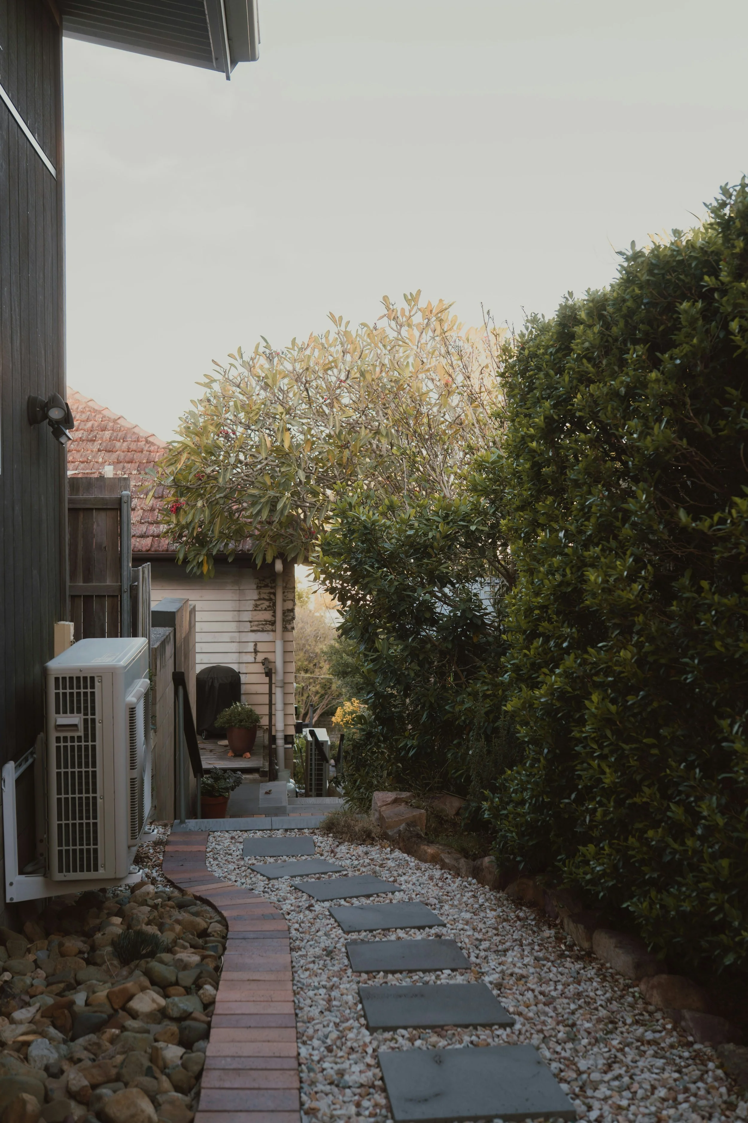 Stone garden path lined with blossom leading to a family home