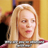A woman with blonde hair and a skeptical expression, asking why someone is so obsessed with her.