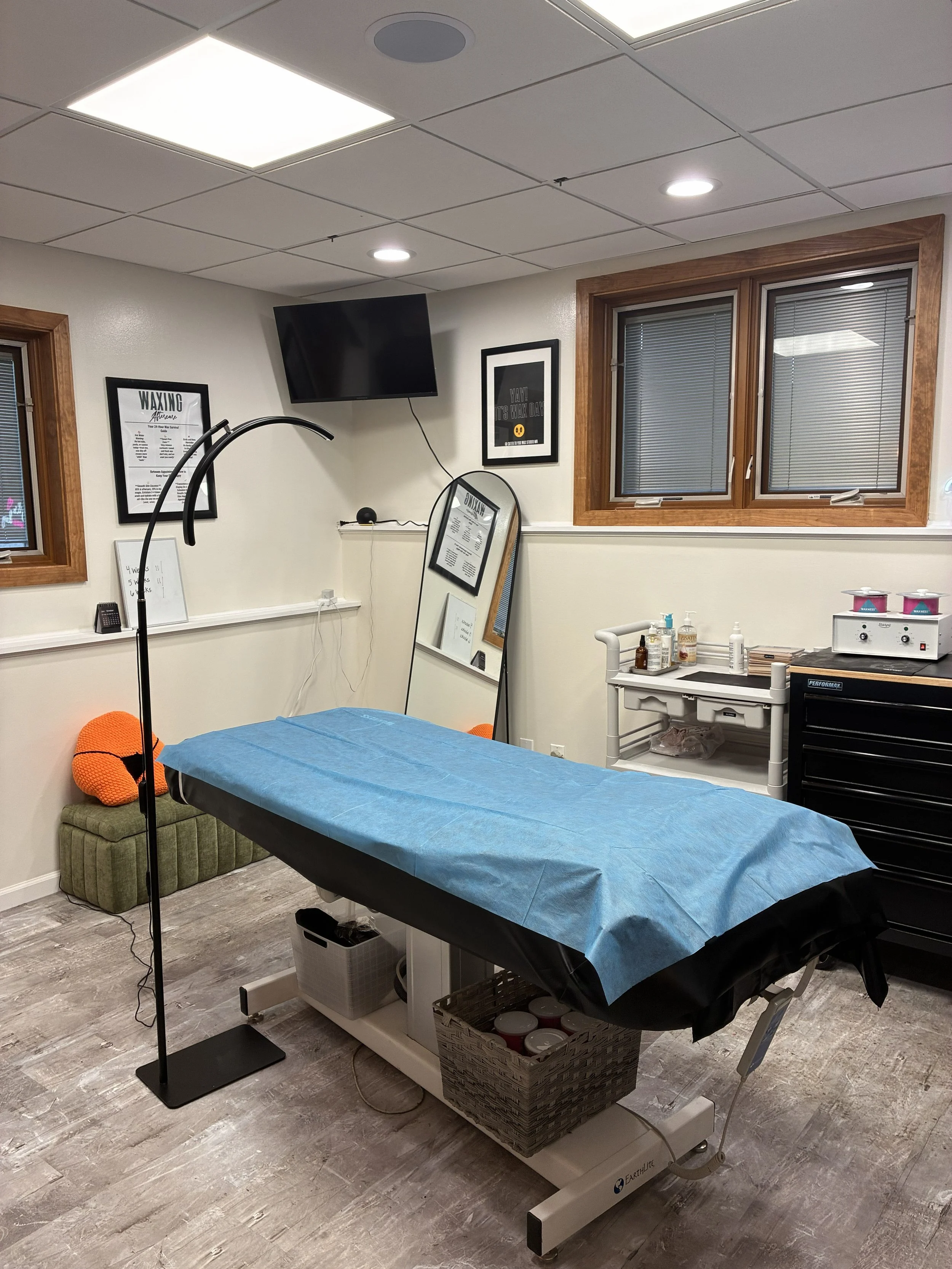 Brazilian waxing treatment room at Cater to You Wax Studio in St. Louis Park, MN, featuring a treatment bed and professional waxing supplies.