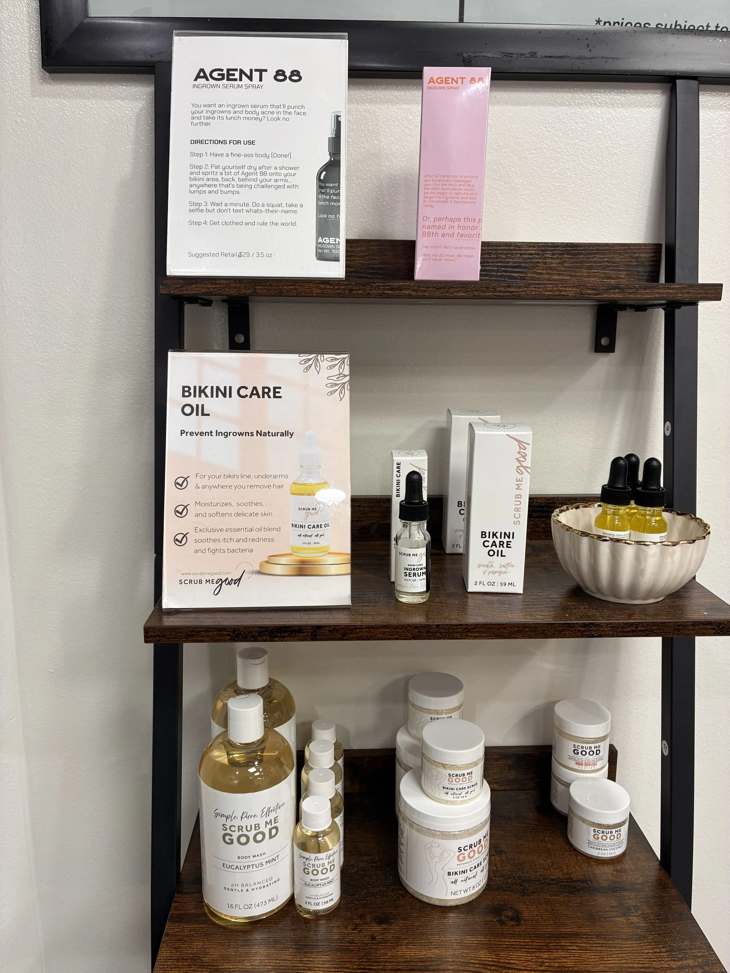 Waxing aftercare products displayed on wooden shelves at Cater to You Wax Studio in St. Louis Park, MN, for post-wax skin care.