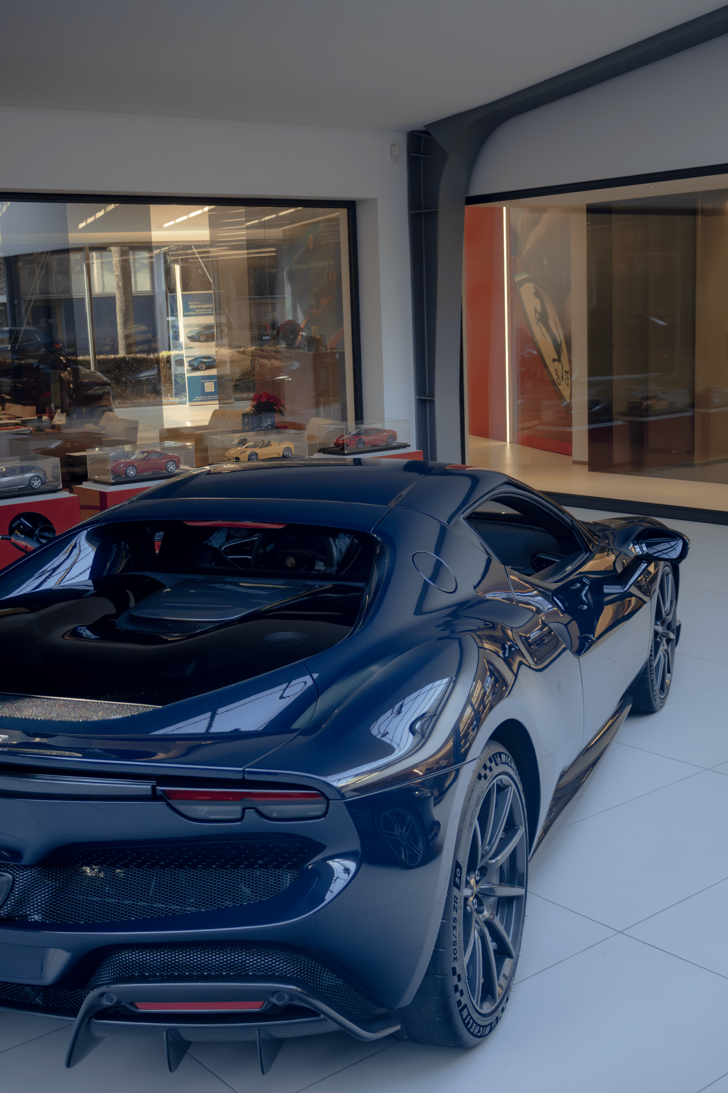 A black and white sports car displayed indoors, with reflections of the interior and windows on its surface.