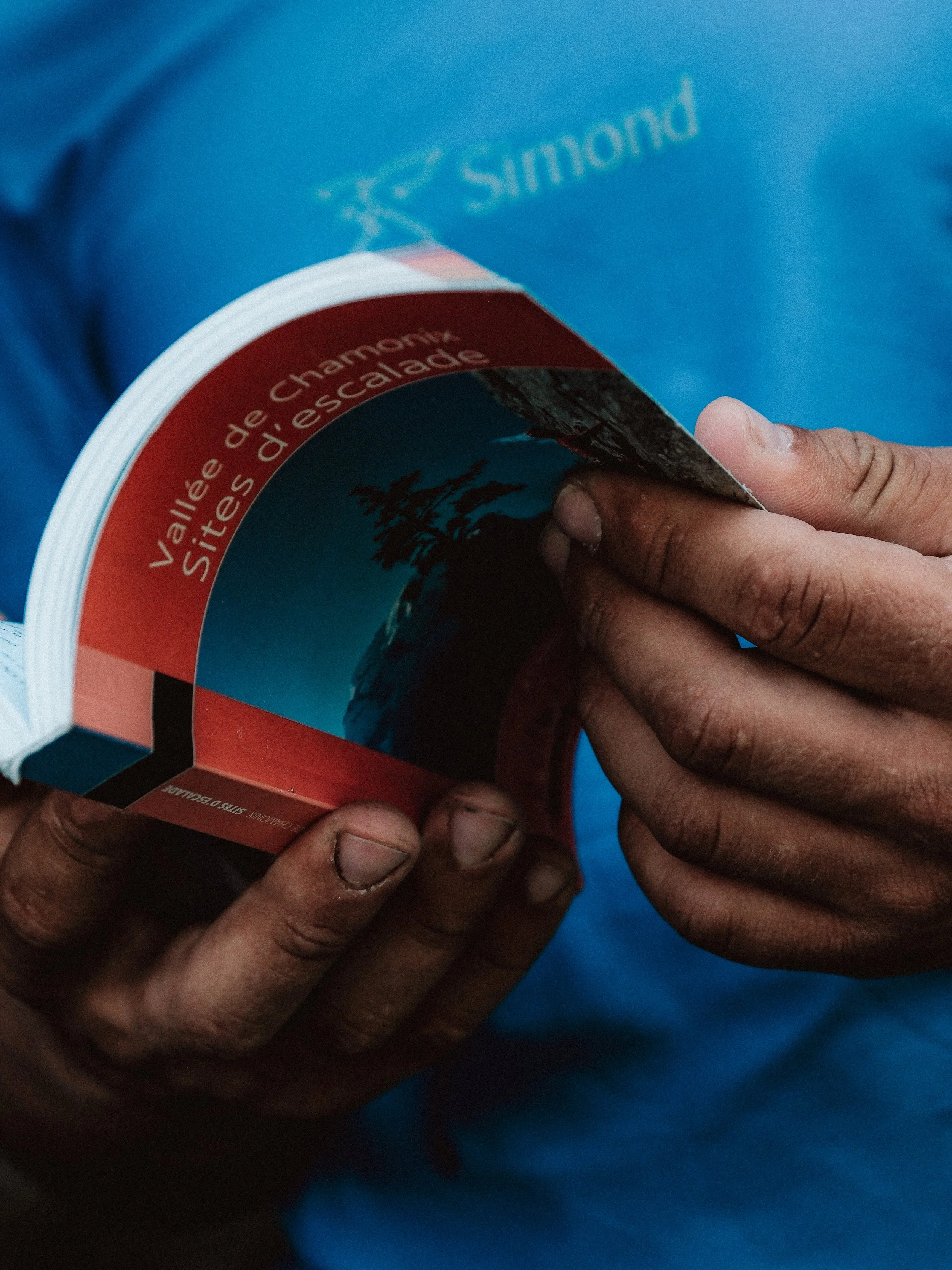 Les mains d'une personne tenant un livre portant un titre en français, avec un arrière-plan bleu.