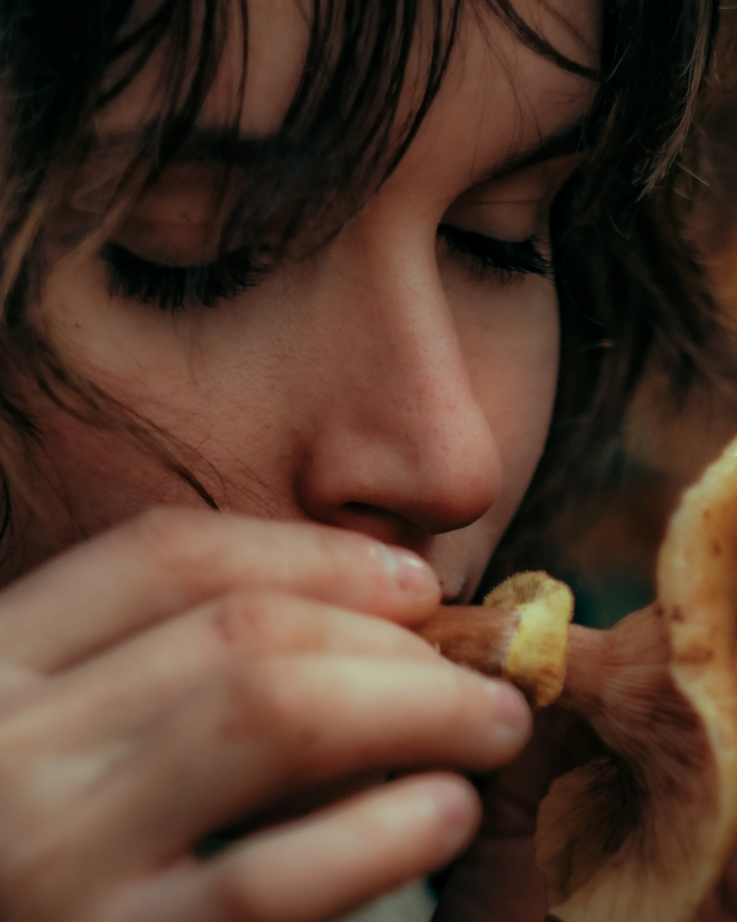 Capture proche d'une femme avec des cheveux bruns foncés, qui tient des chips dans ses mains et semble apprécier manger.