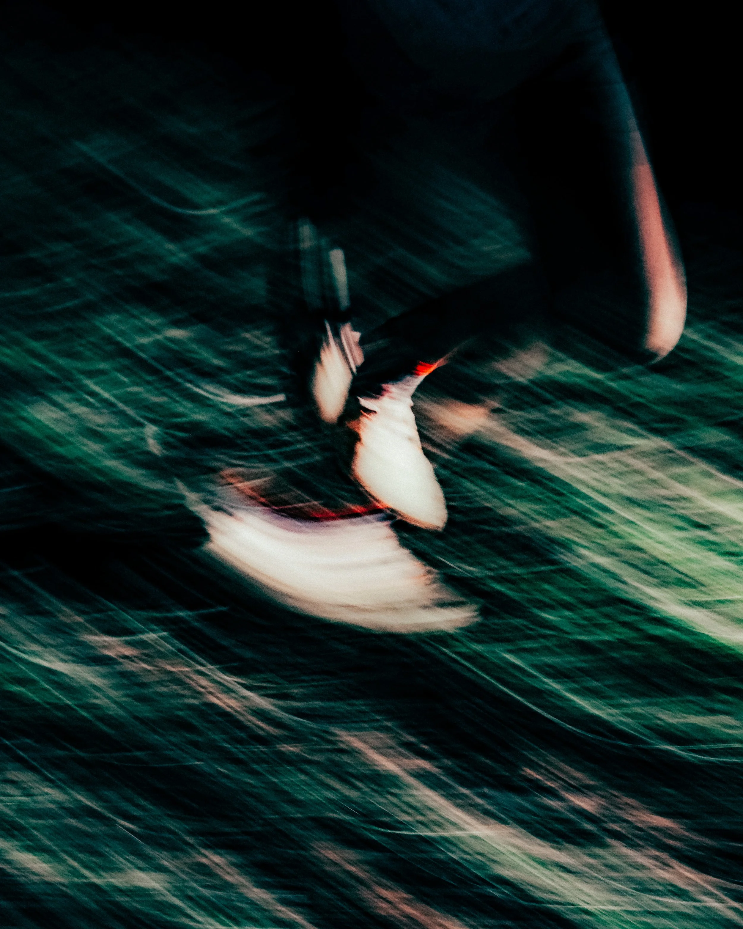 Une photographie floue et en mouvement d'une personne proche d'une lampe ou d'une source de lumière dans un environnement sombre.