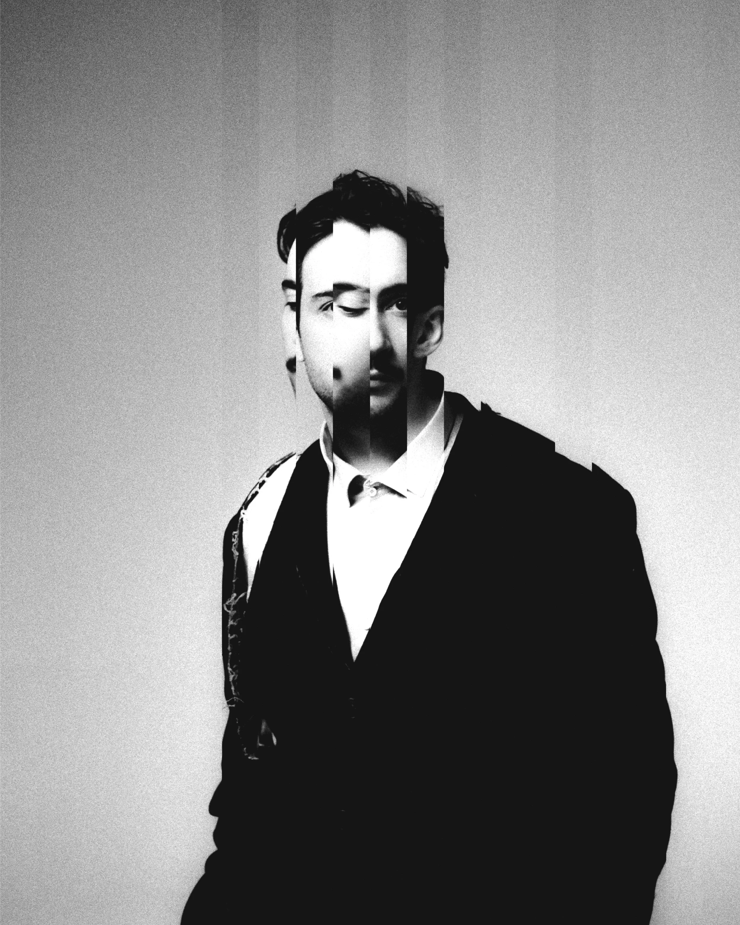 Portrait en noir et blanc d'un homme habillé en costume avec un nœud papillon, ses traits faciaux sont déformés par un effet de fragmentation visuelle.