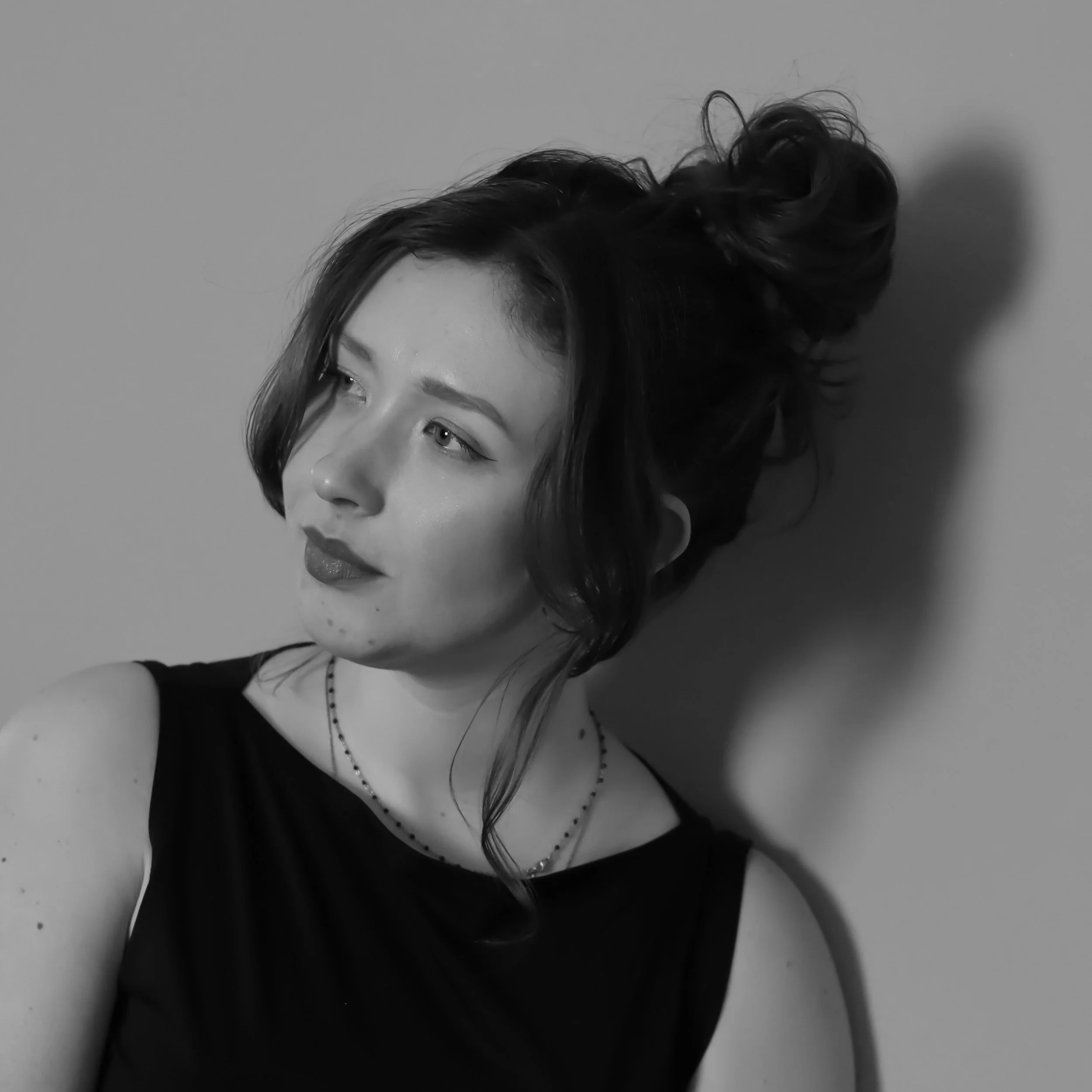 Een zwart-wit foto van een vrouw met lang haar die op haar schouder ligt, met haar gezicht gedeeltelijk zichtbaar en haar haar omhoog gestyled.