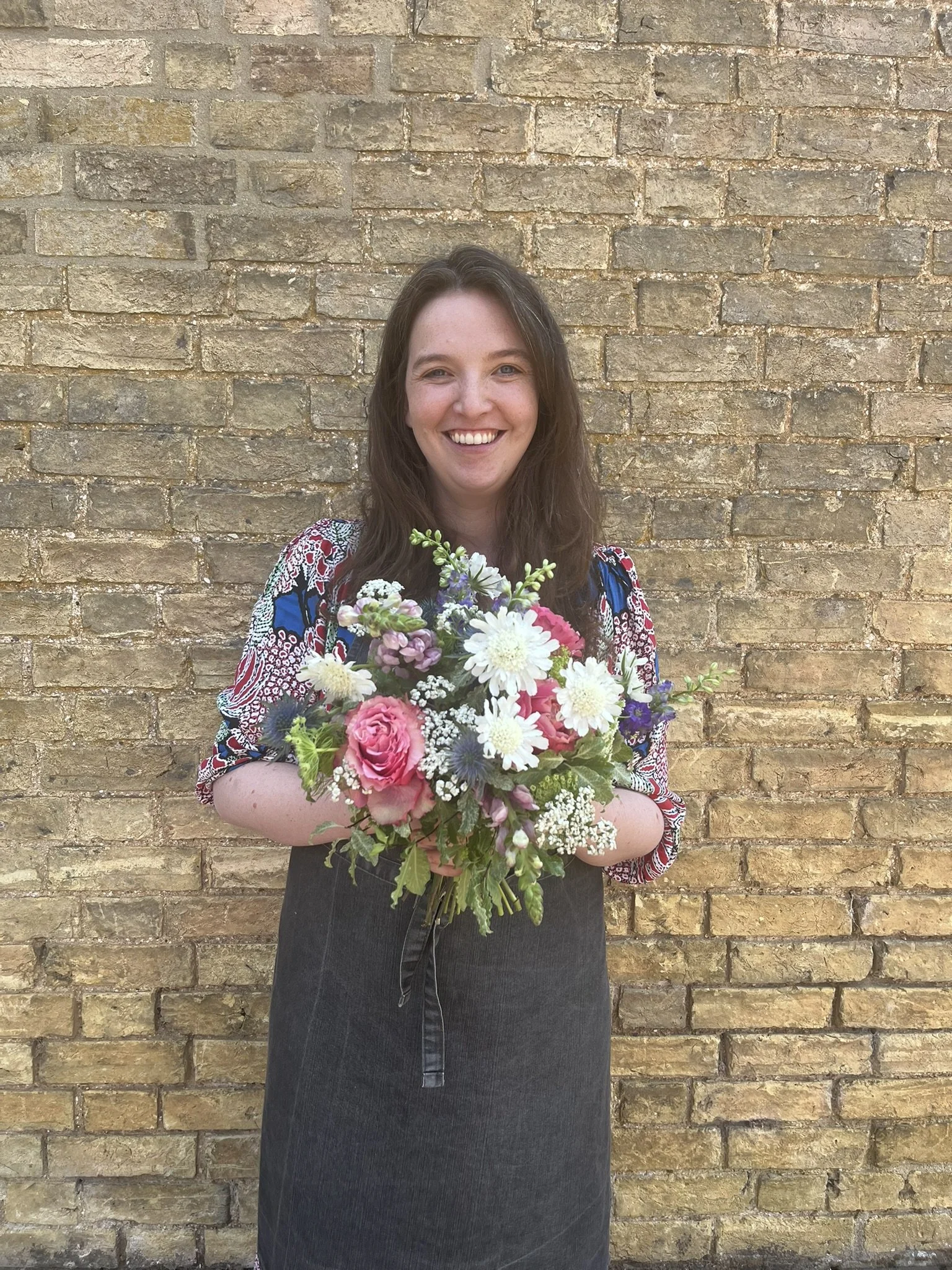 Founder of Jessica Holly Floral holding floral bouquet with roses, scabiosa and alchemila