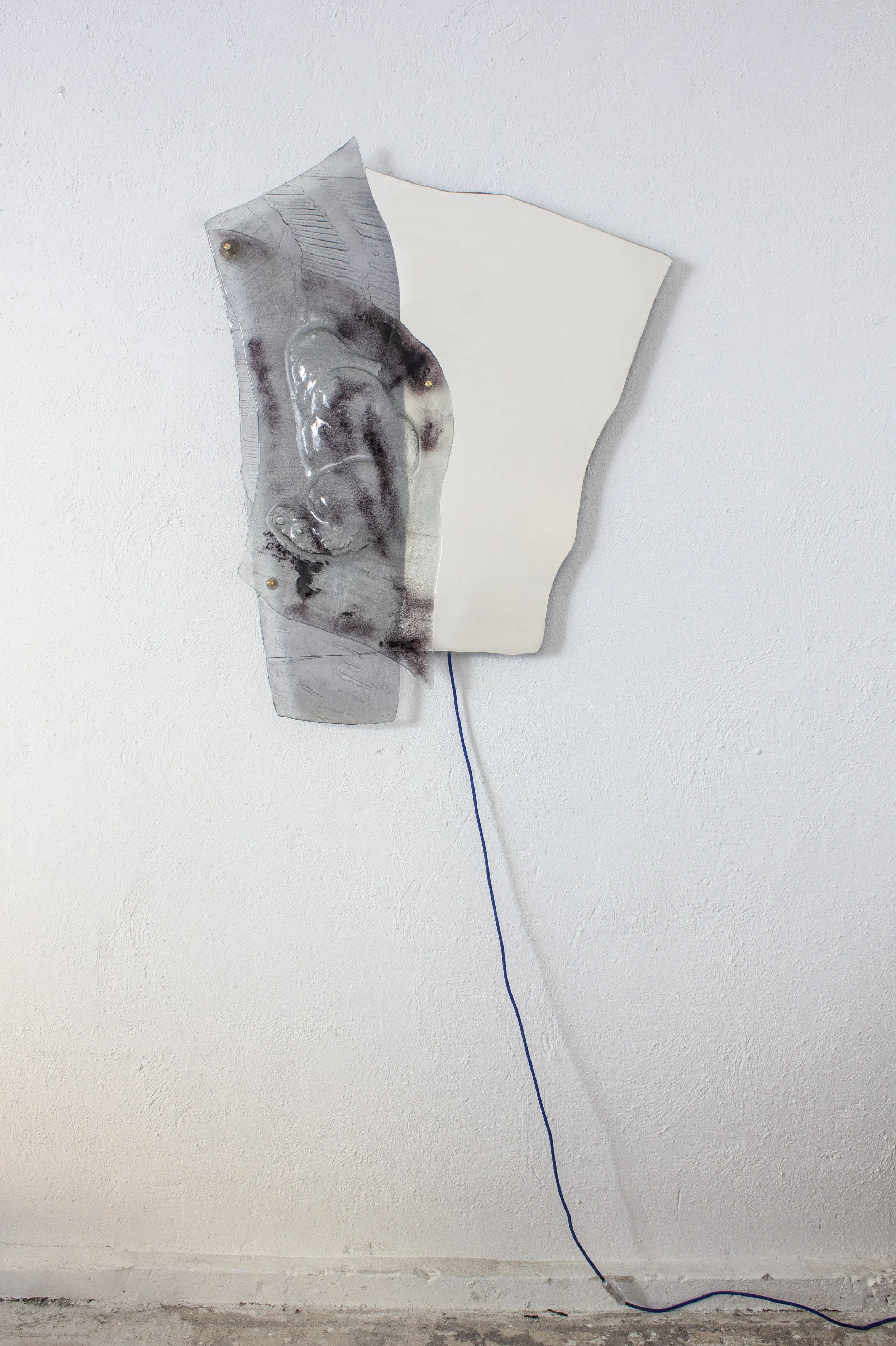 Un'opera d'arte moderna composta da una lastra di vetro irrigidita e una lastra di plastica bianca, attaccate alla parete.