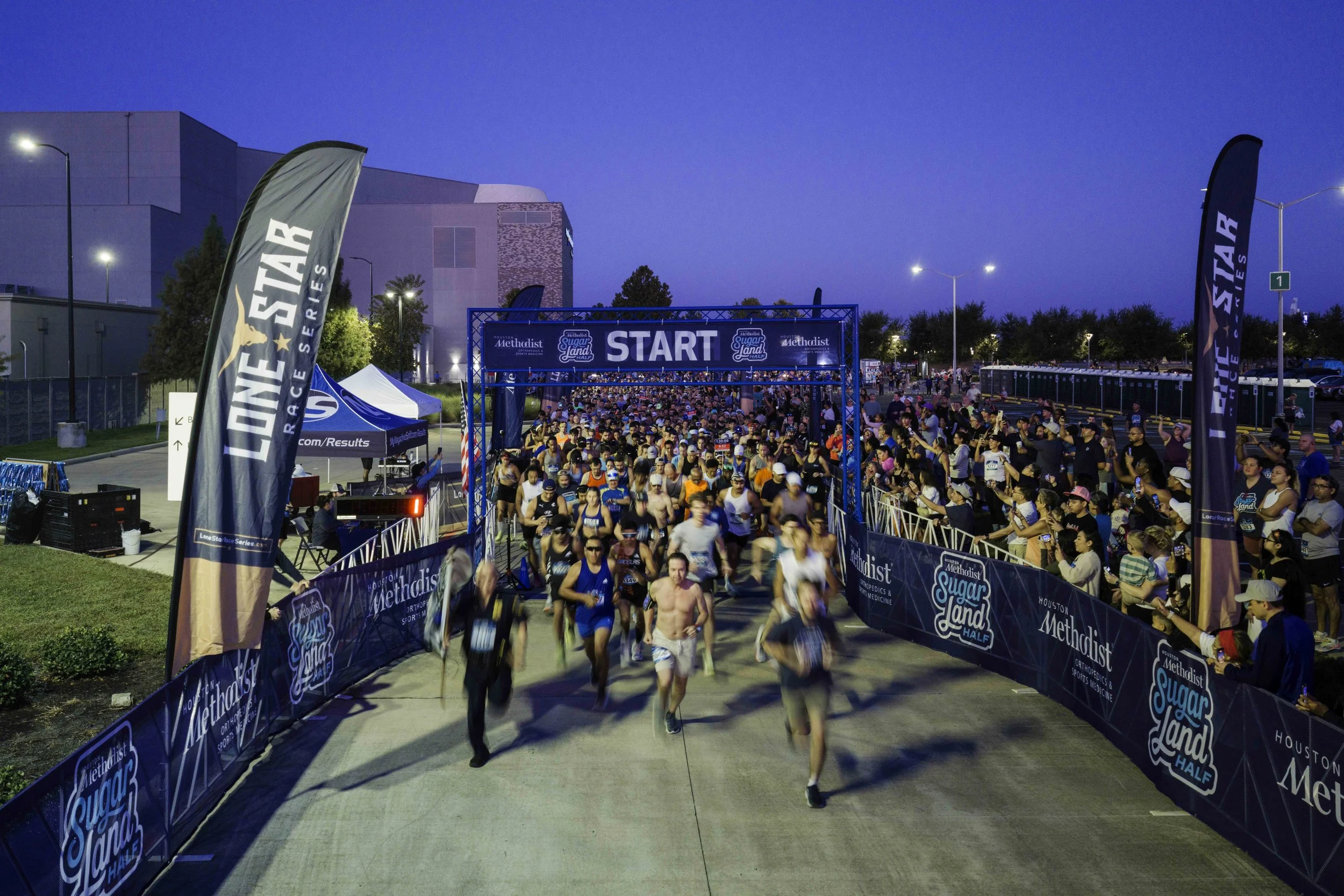 Runners surging through the Sugar Land starting arch