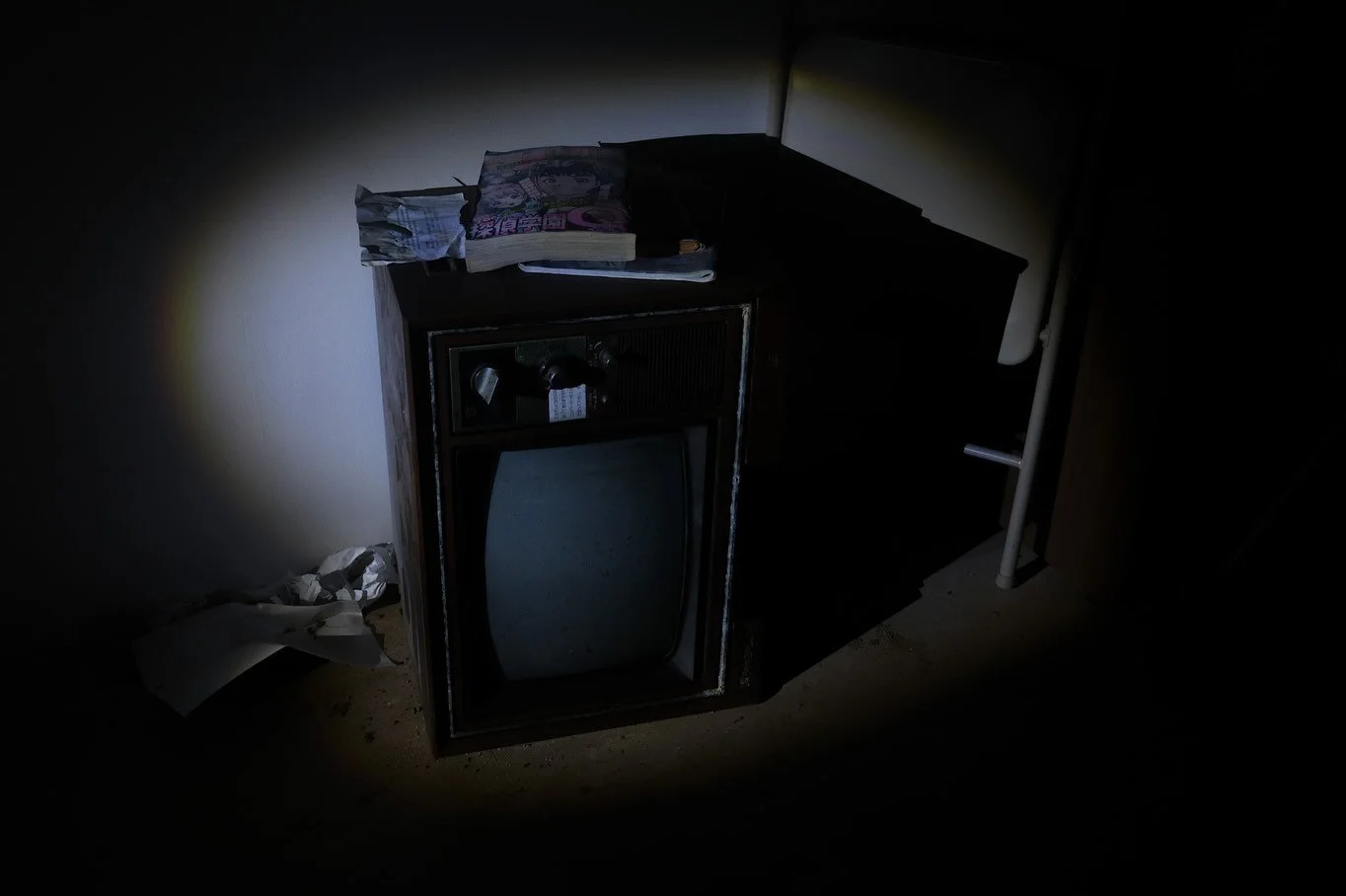Old television set and magazines illuminated by flashlight inside the Ghosts of Tomorrow  installation, Kinugawa Onsen.