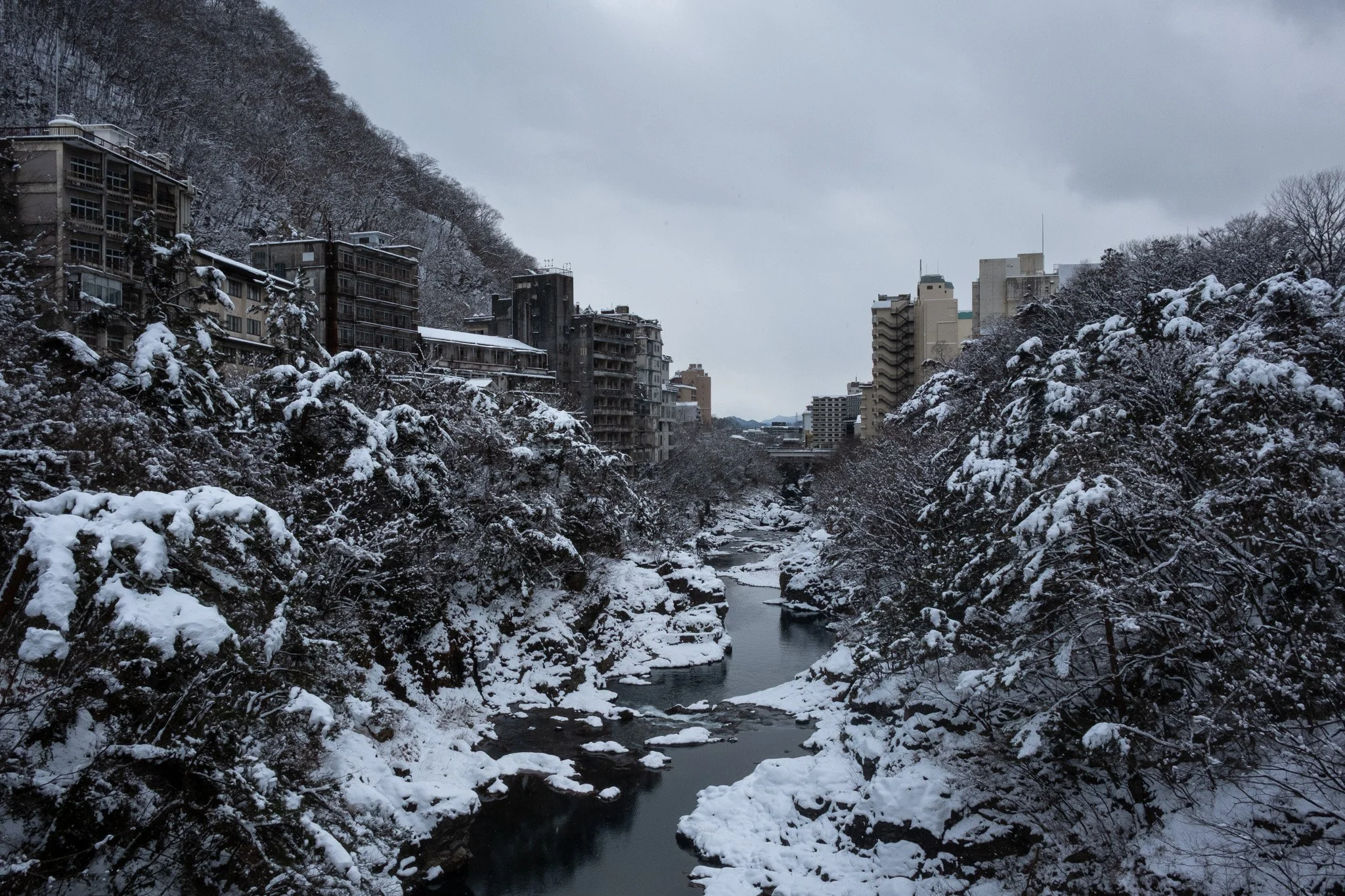 Snow-covered Kinugawa Onsen valley with hotels lining the river gorge.