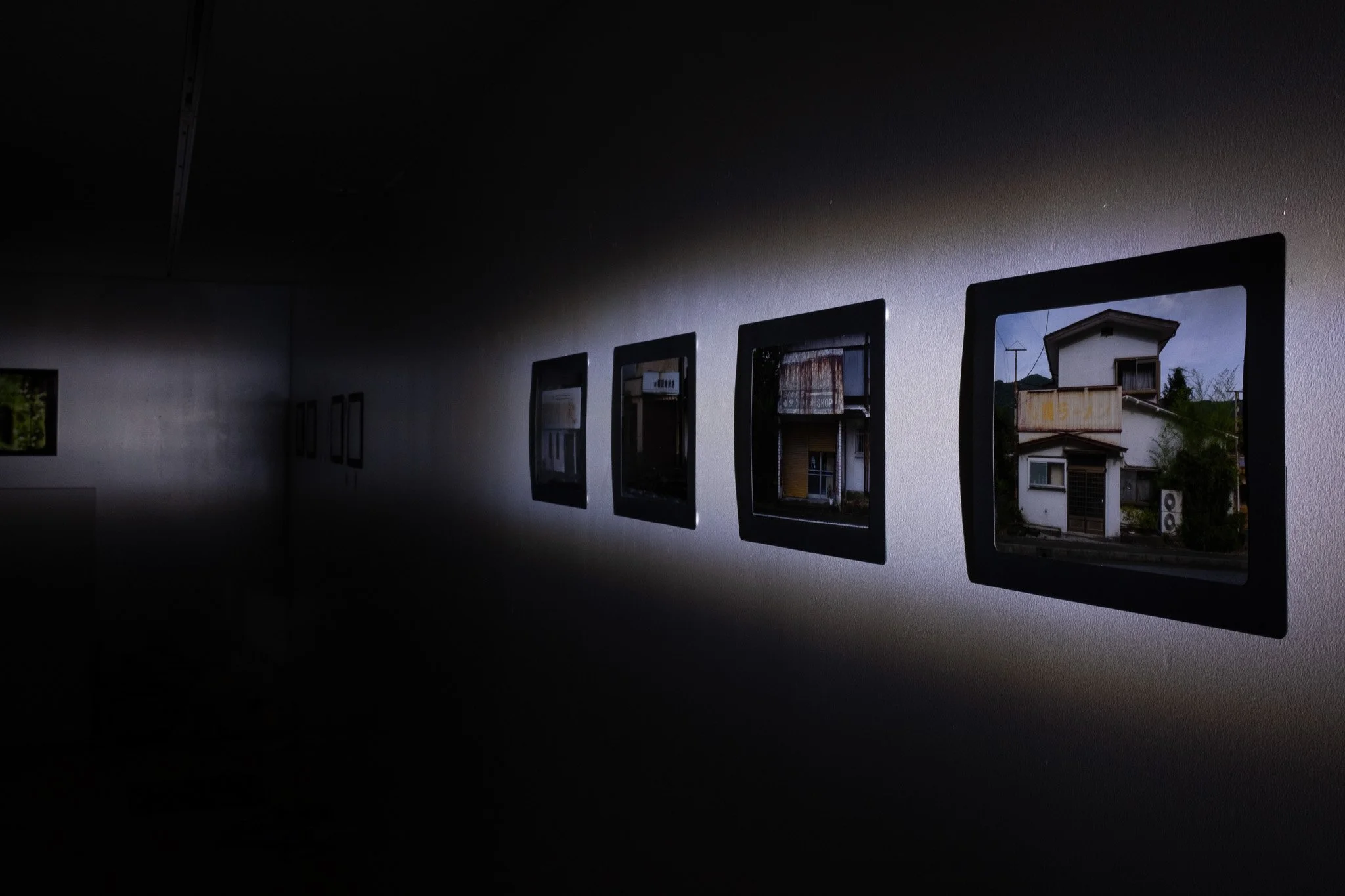 Framed photographs of Kinugawa Onsen displayed along a dark gallery wall during Ghosts of Tomorrow.