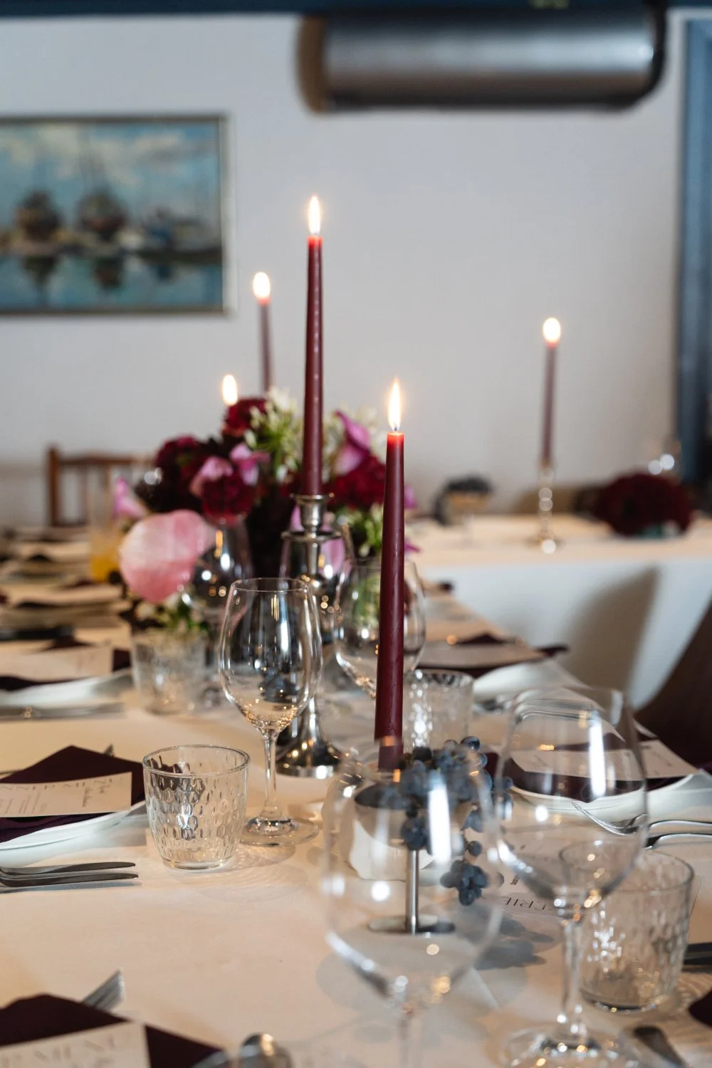 Elegant dining table setting with lit candles, wine glasses, and floral centerpieces.