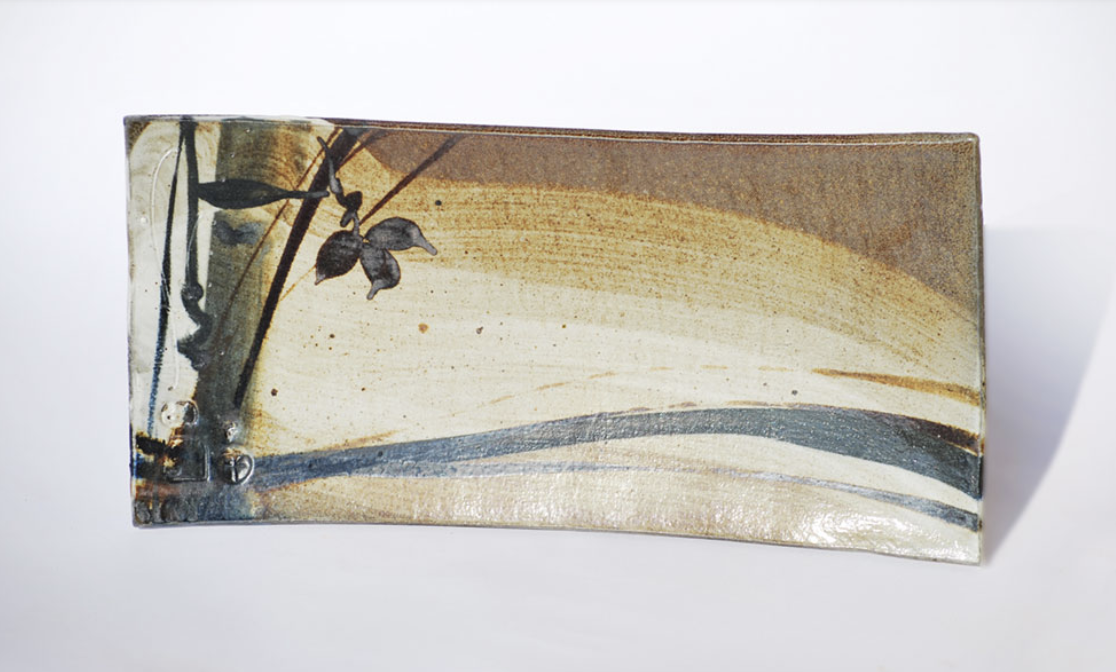 Decorative ceramic sushi plate with abstract landscape design in earth tones, including brown, beige, and gray, with a bamboo motif on the left side.