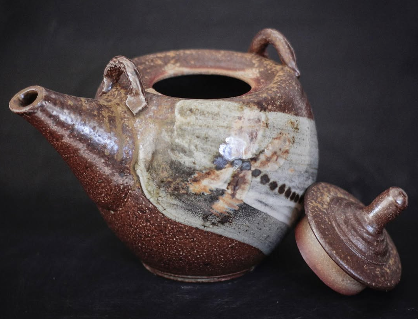 Ceramic teapot with a removable lid on a dark background. Food and dishwasher safe. 