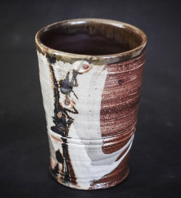 Ceramic mug with a brown and white sumi-e  bamboo design,  placed on a dark surface.