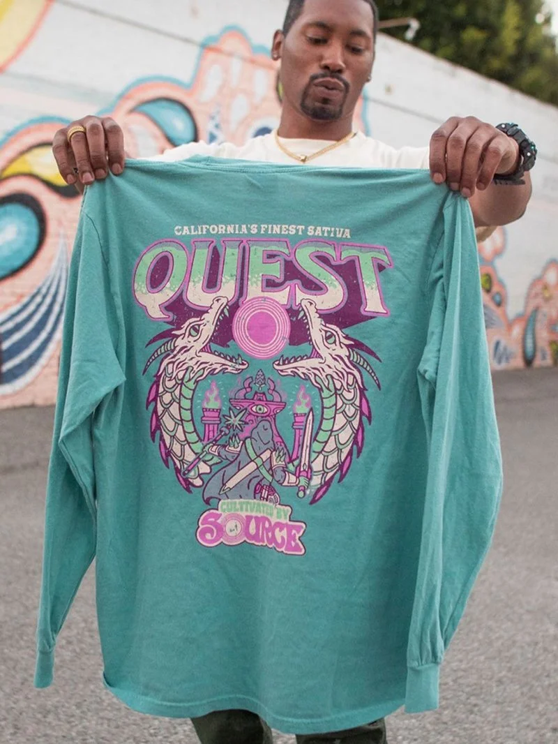 Person holding up a turquoise long-sleeve shirt with "QUEST California's Finest Sativa" and a graphic design featuring dragons and mystical elements. The text "Cultivated by Source" is also visible.