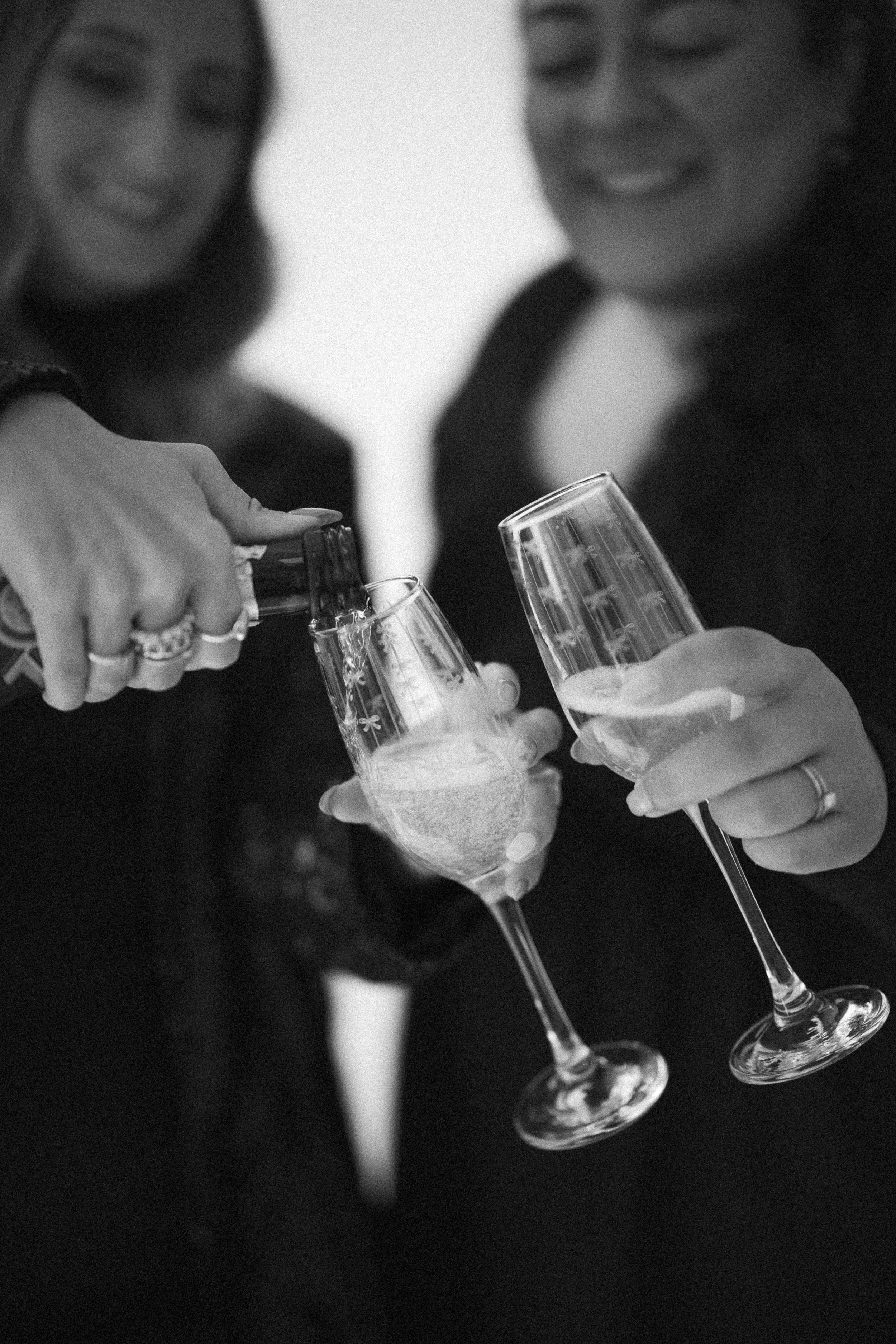 Two women smiling and clinking champagne glasses, celebrating with drinks.