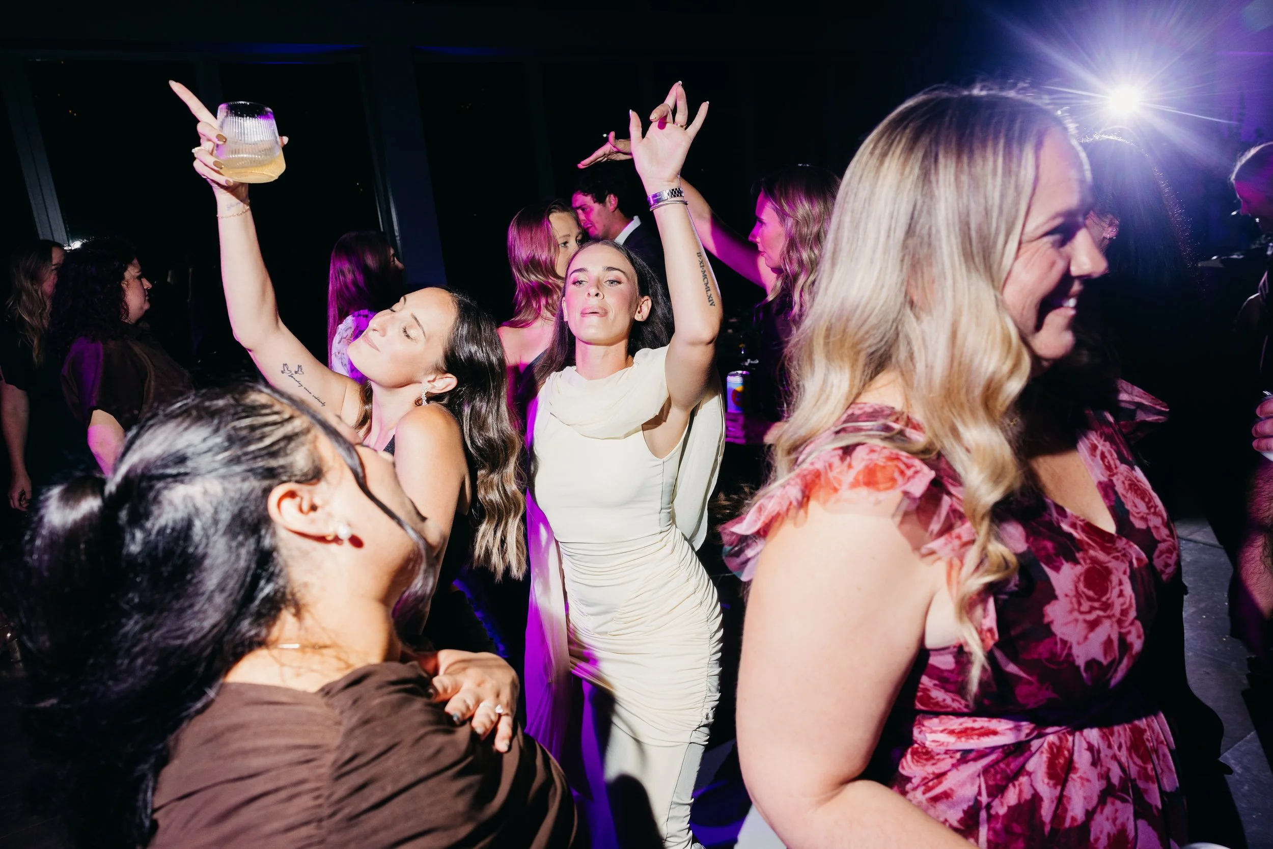 People dancing and enjoying themselves at a party with colorful lighting.