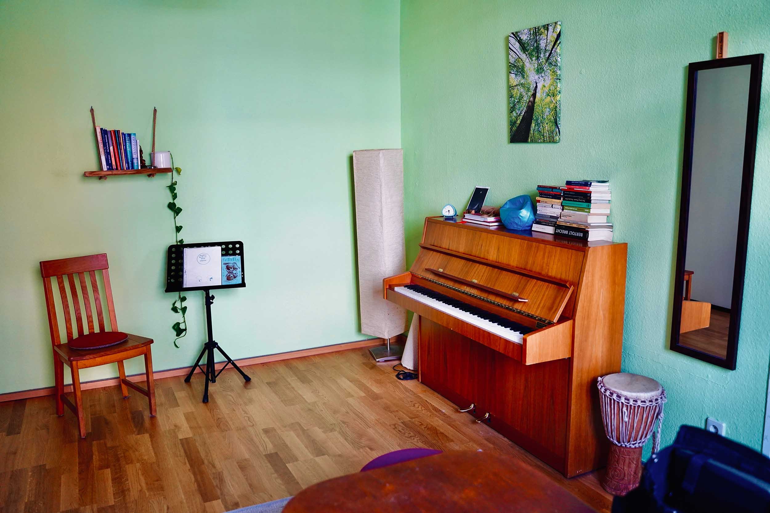 Heller Therapieraum mit Klavier, Trommel, Spiegel und Notenständer, Stimmtherapie für Kinder und Jugendliche in Köln-Ehrenfeld