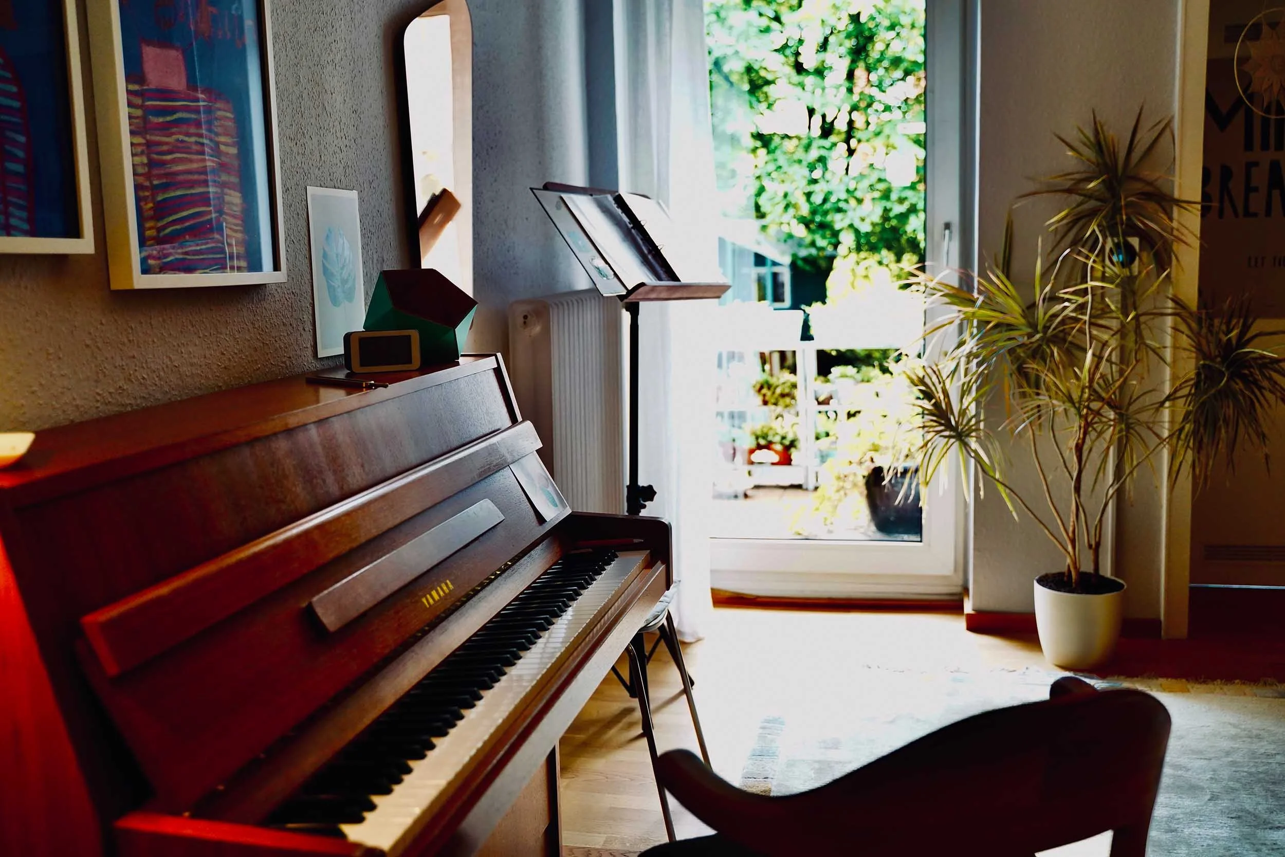 Therapieraum mit Klavier, Notenständer und Blick auf den Balkon, Stimmtransition in Köln-Ehrenfeld