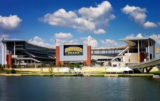 Baylor Bears stadium with water in the foreground under a partly cloudy sky.