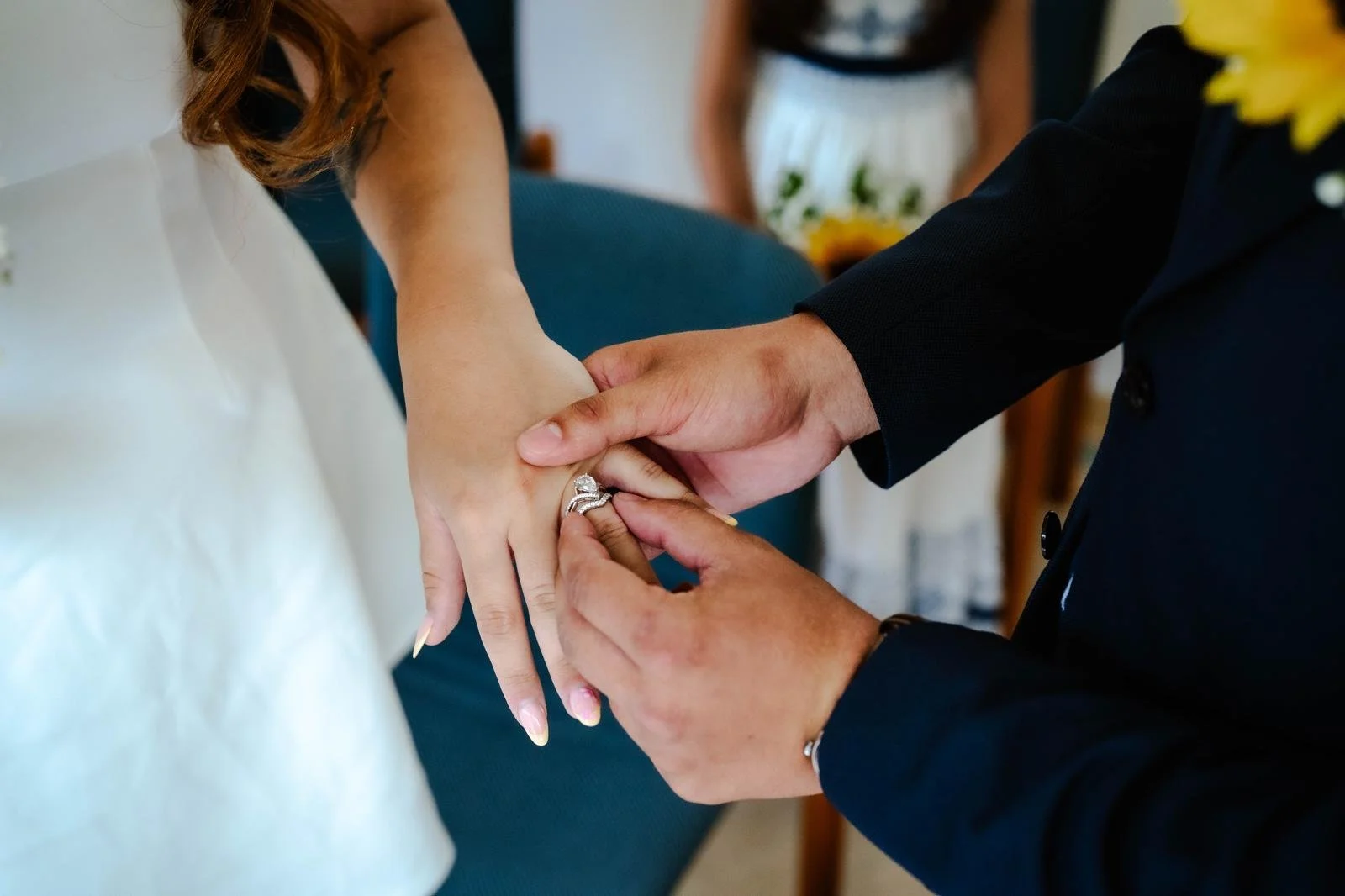 A groom places a wedding ring on a bride's finger during a wedding ceremony.