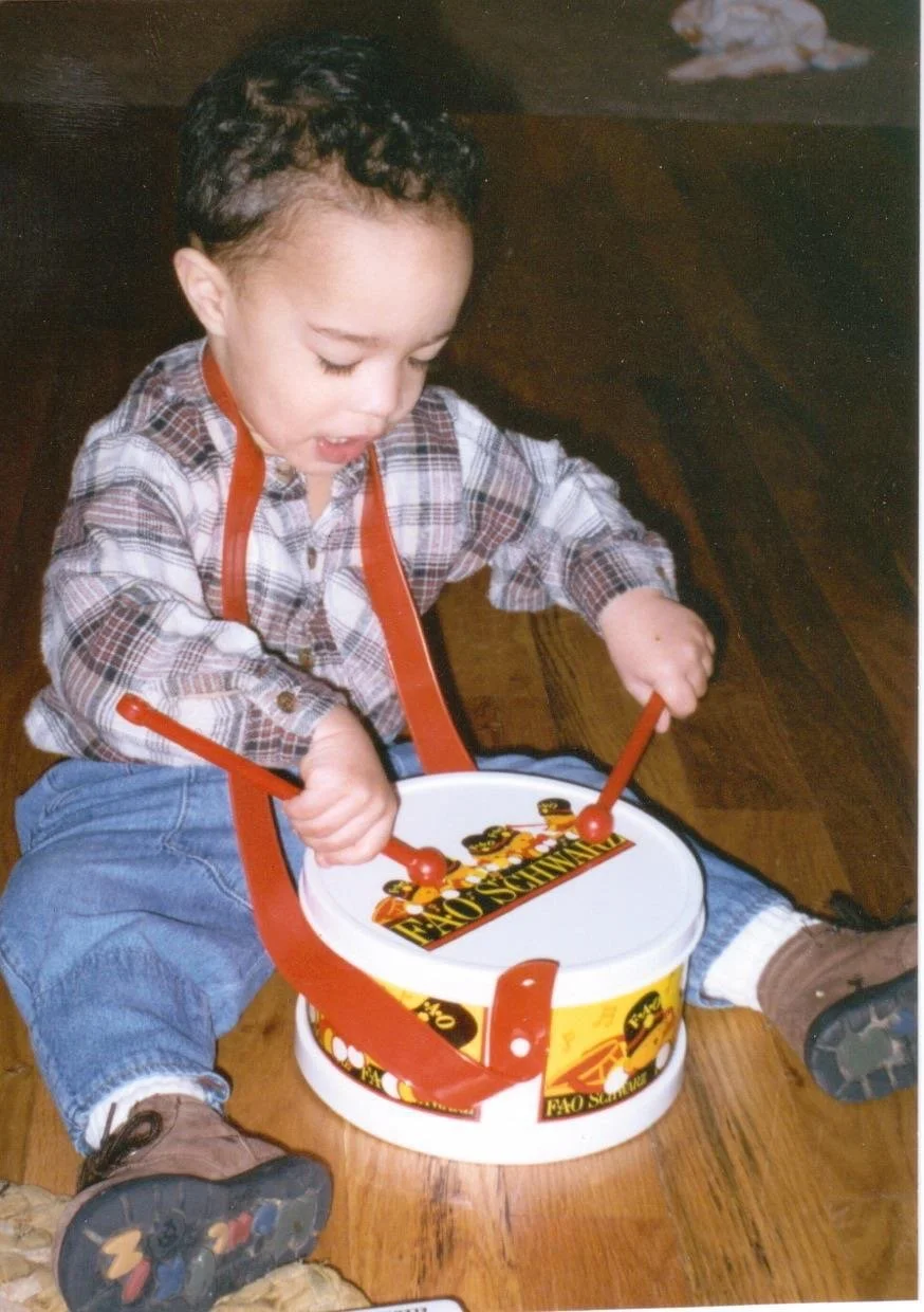 Young boy sitting on the floor playing a toy drum