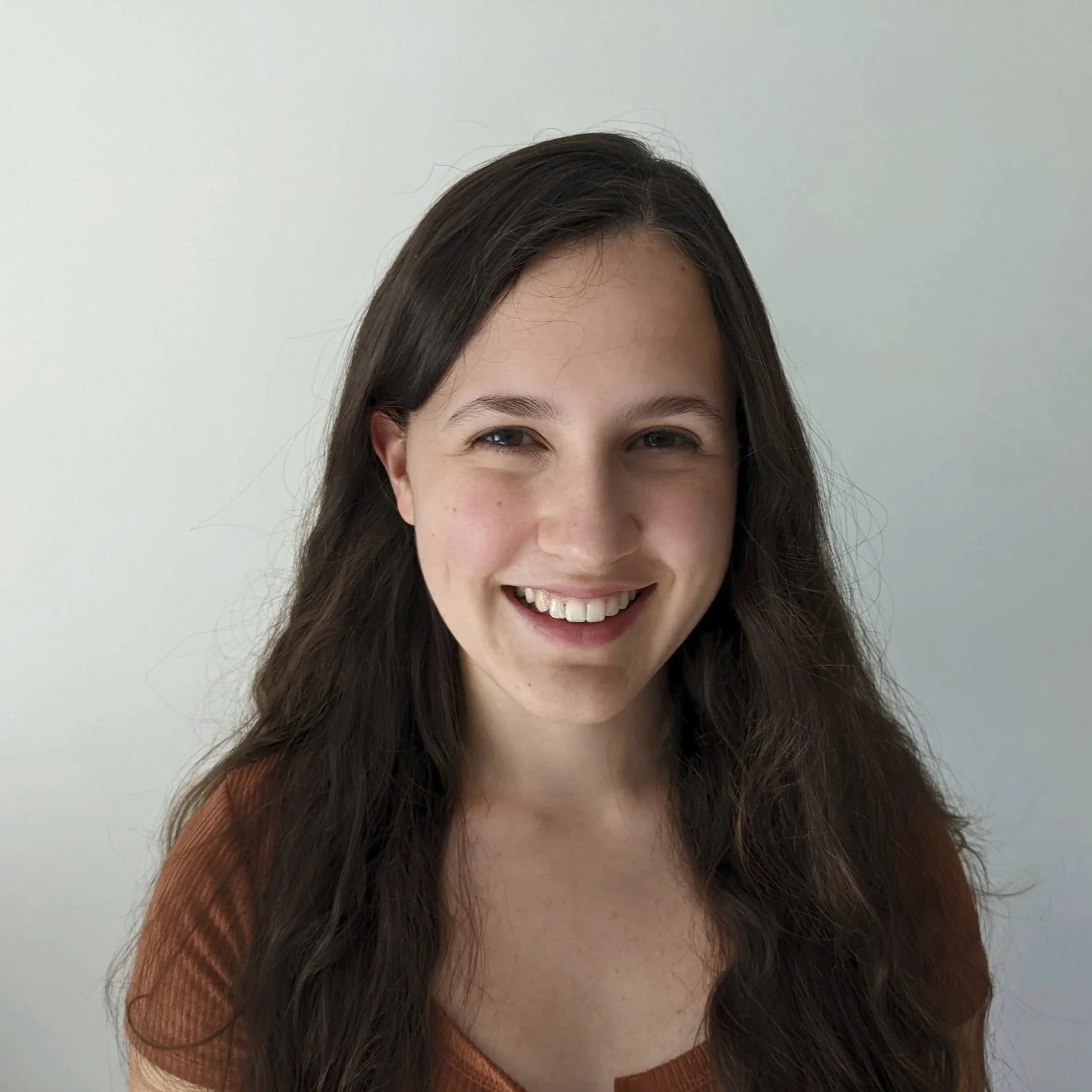 Julia Mitra, a woman with long, dark hair smiling in front of a plain light-colored wall. Julia Mitra is a battery researcher at Imperial College London working in high-performance sodium ion batteries.