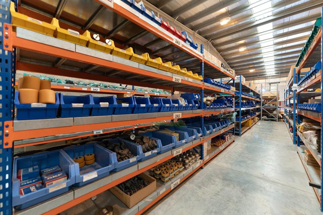 Organized warehouse shelving with bins of industrial parts and supplies for inventory management and replenishment.