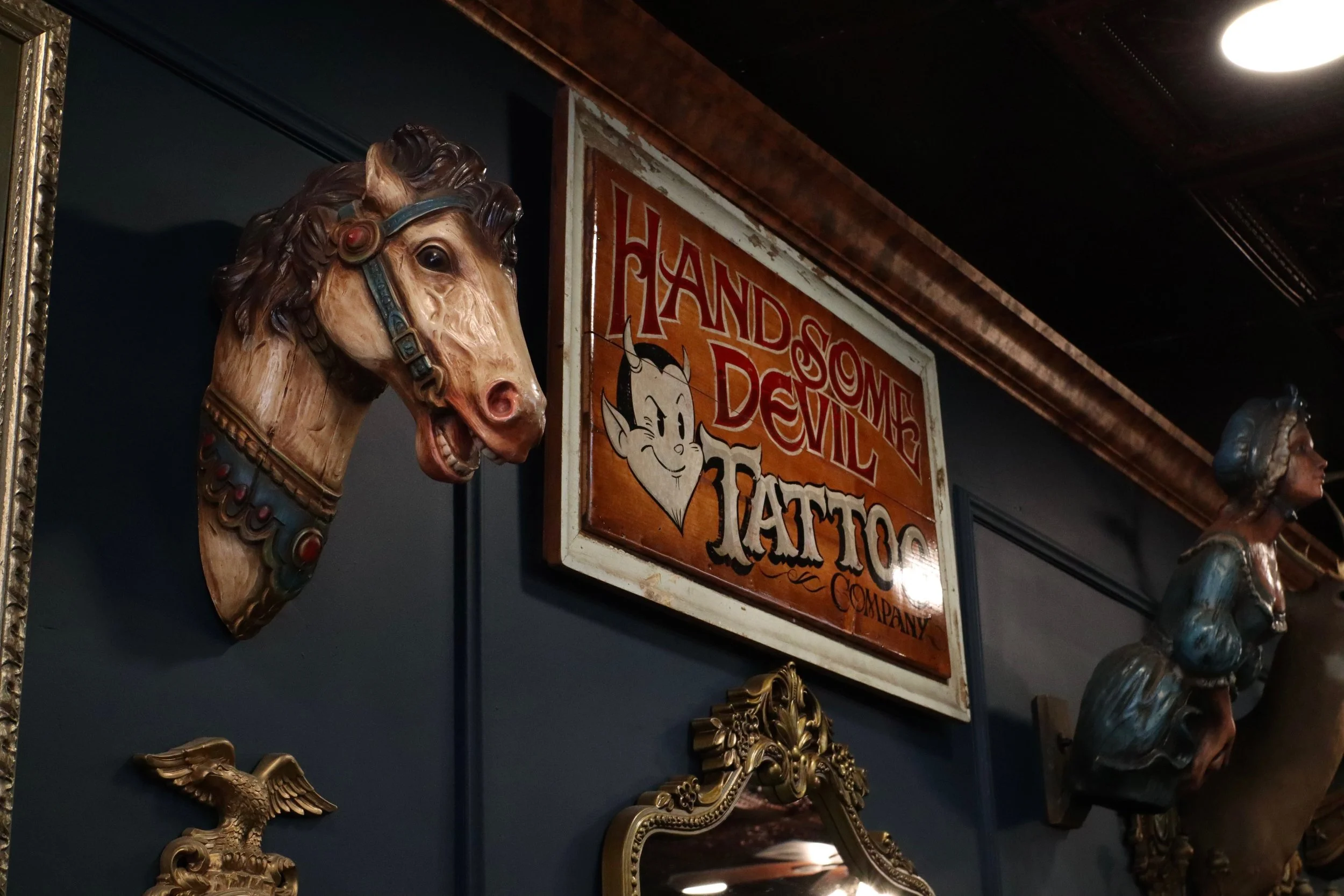 Vintage decor and Handsome Devil Tattoo Company sign displayed inside the tattoo studio in Saddle Brook, New Jersey.