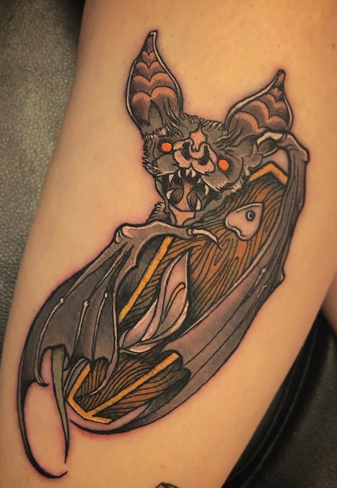 Tattoo of a moth with a skull face and antennae, resting on a flower with detailed petals.